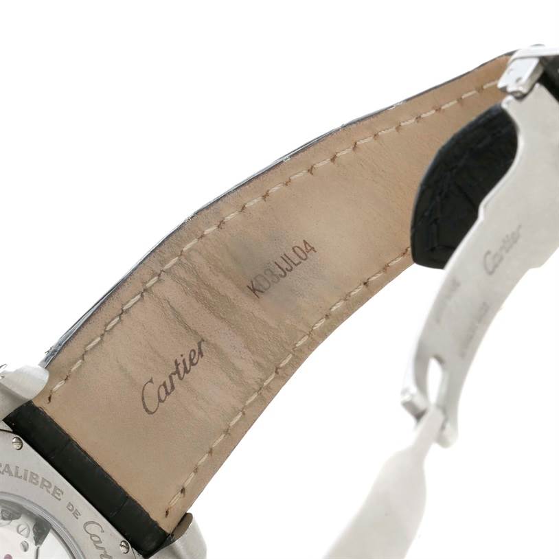 This image displays the interior leather side of the strap and a partial view of the case back of the Calibre de Cartier model by Cartier.