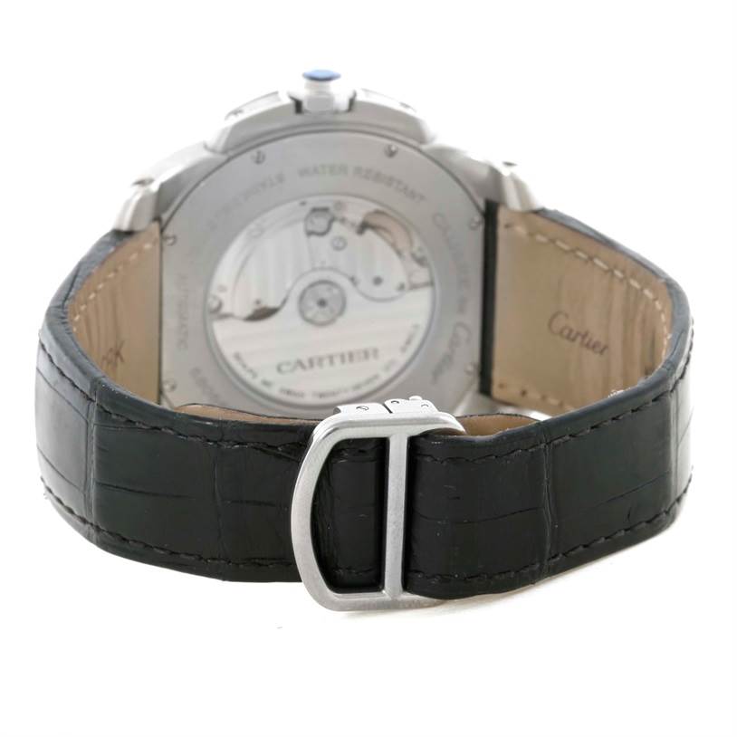 The image shows the back view of the Calibre de Cartier watch by Cartier, highlighting its open case back and leather strap with buckle.