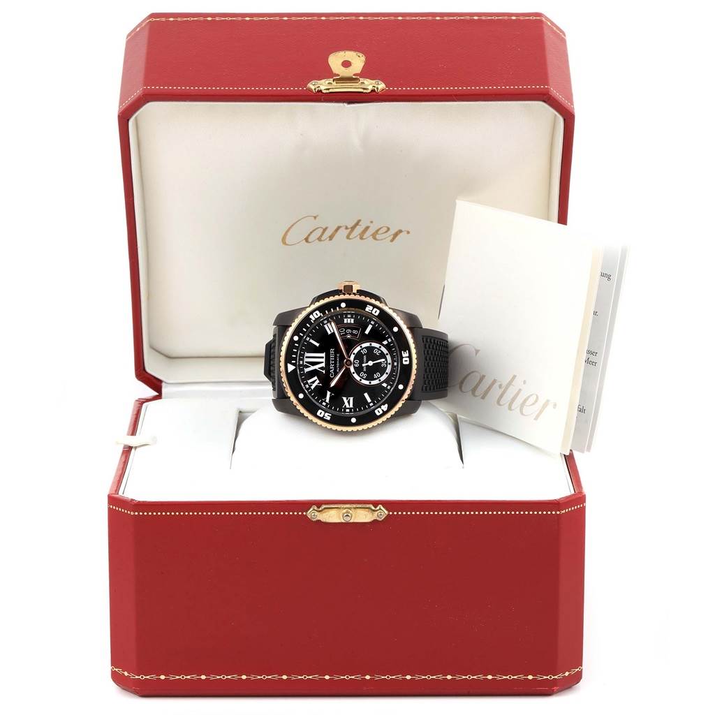The image shows the Calibre de Cartier watch by Cartier in an open red box with a booklet beside it.