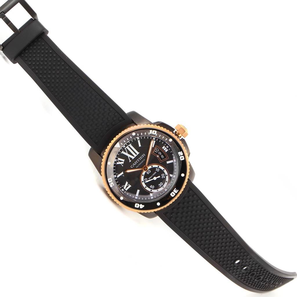 The image shows a top view of the Calibre de Cartier watch by Cartier, highlighting its black rubber strap and detailed dial.