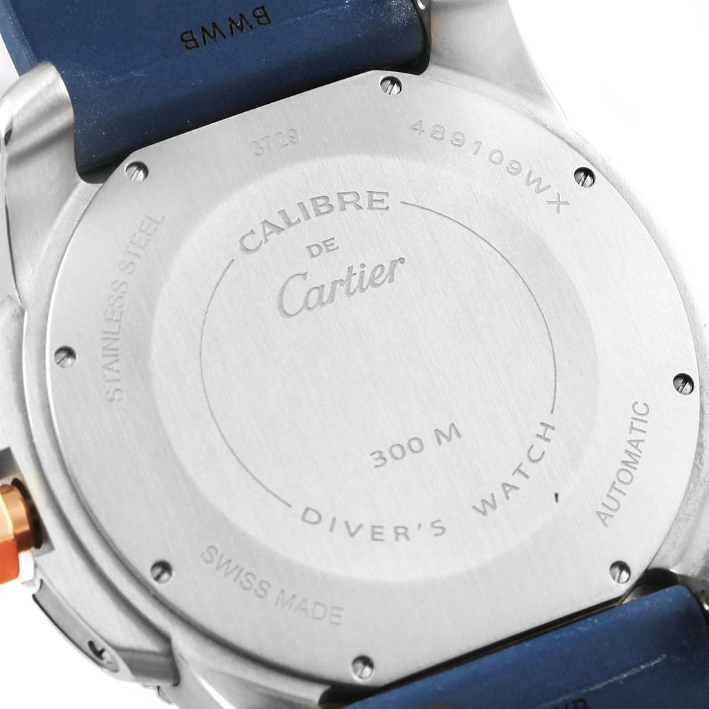The image shows the back case of a Calibre de Cartier watch by Cartier, displaying its engravings and part of the blue strap.