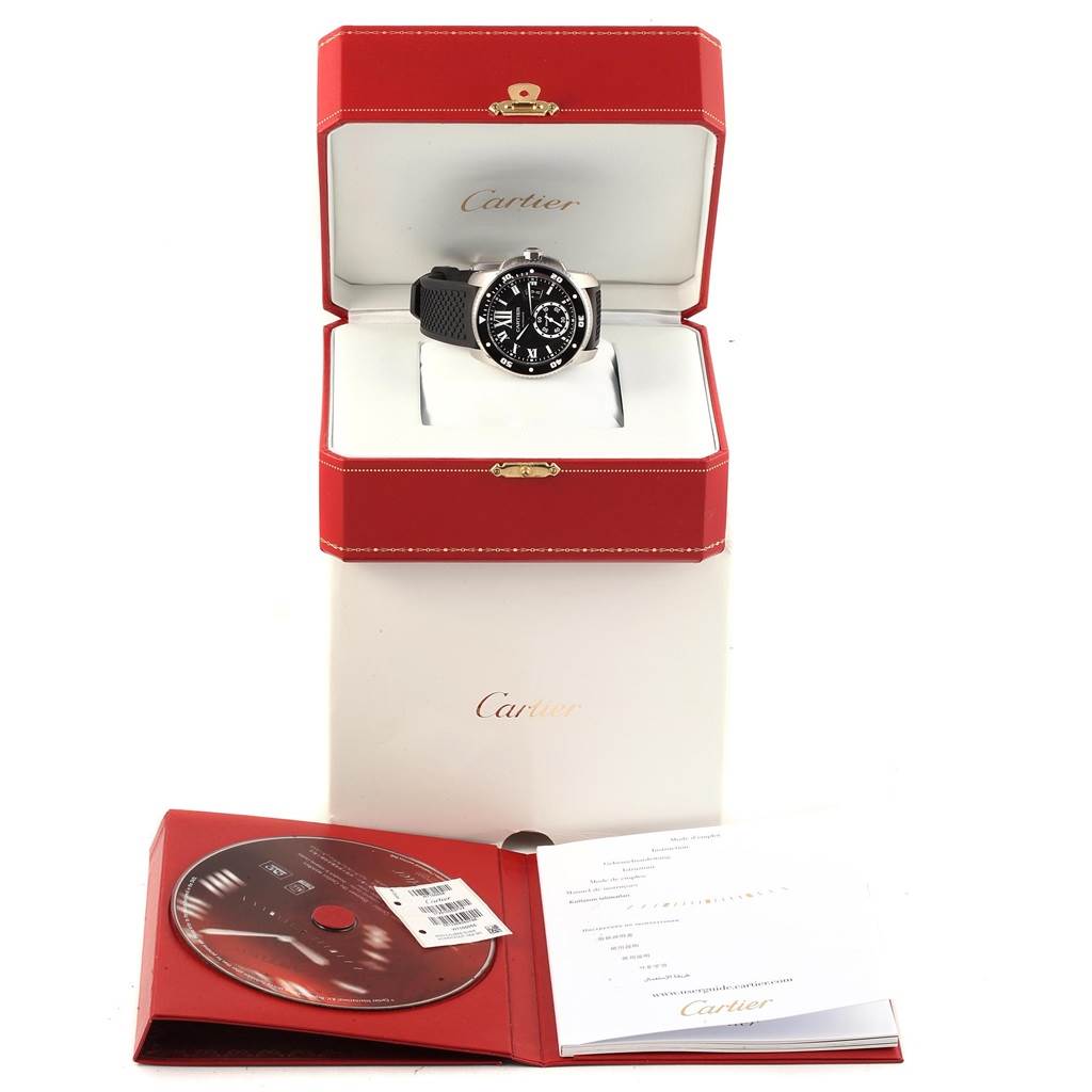 The Calibre de Cartier watch by Cartier is shown front-facing inside its open red box with accompanying documents and a CD.
