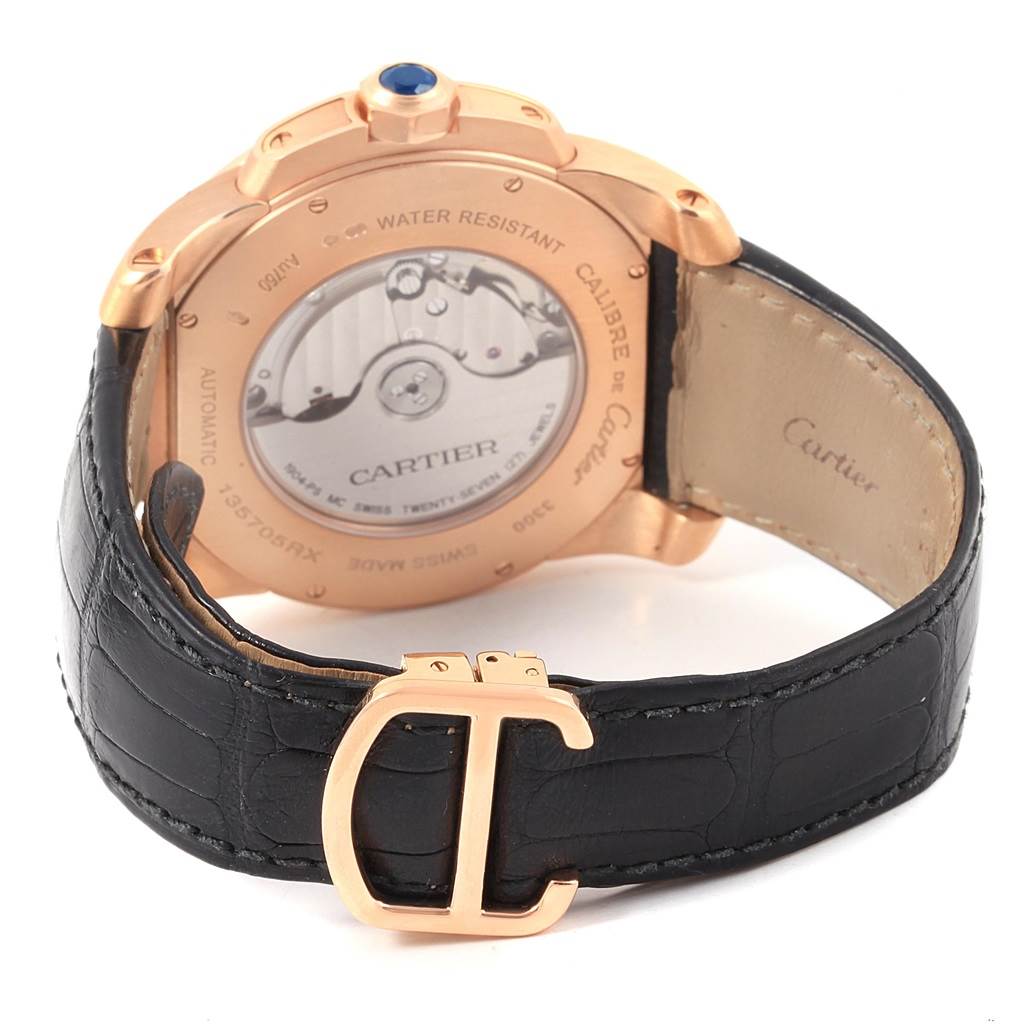 The image shows the Calibre de Cartier watch by Cartier from the back, highlighting the automatic movement and the leather strap with a buckle.