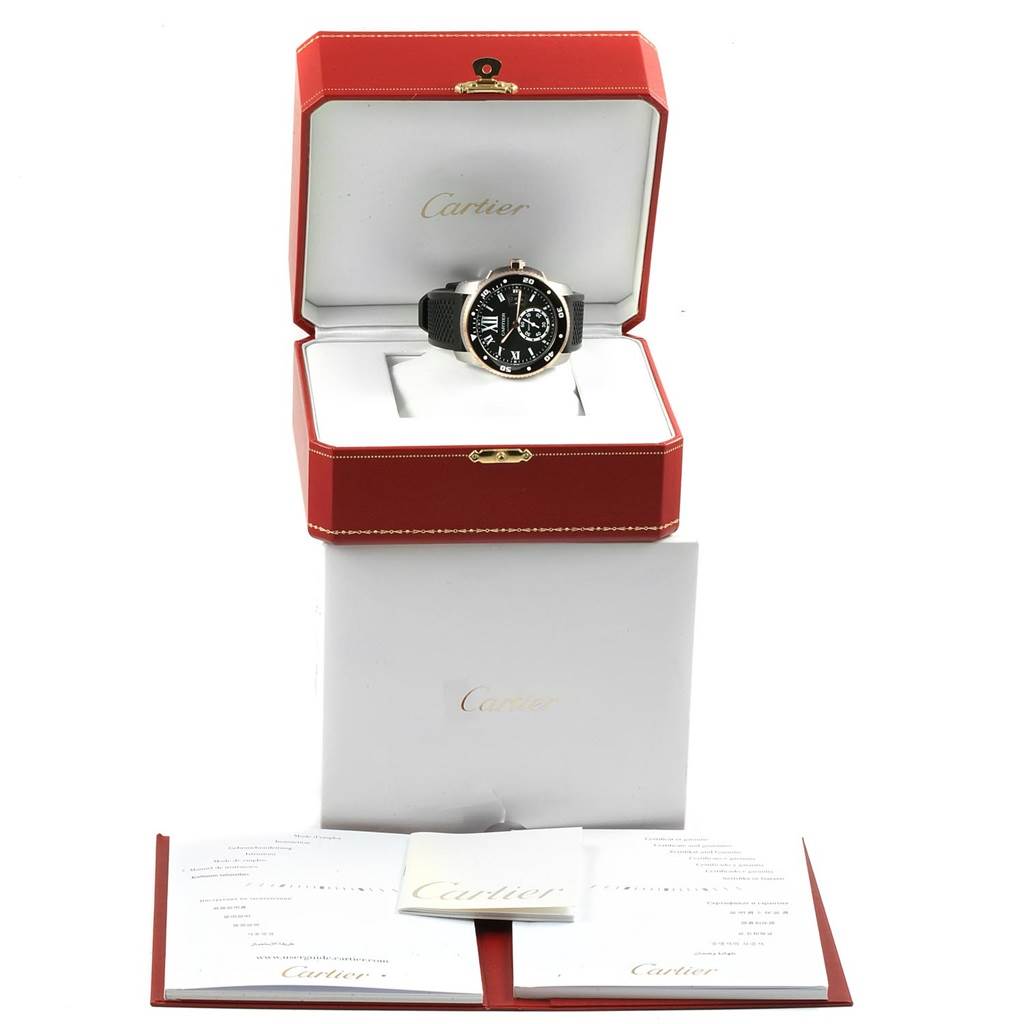 The Calibre de Cartier watch by Cartier is shown in a red open box with accompanying documents displayed in front.