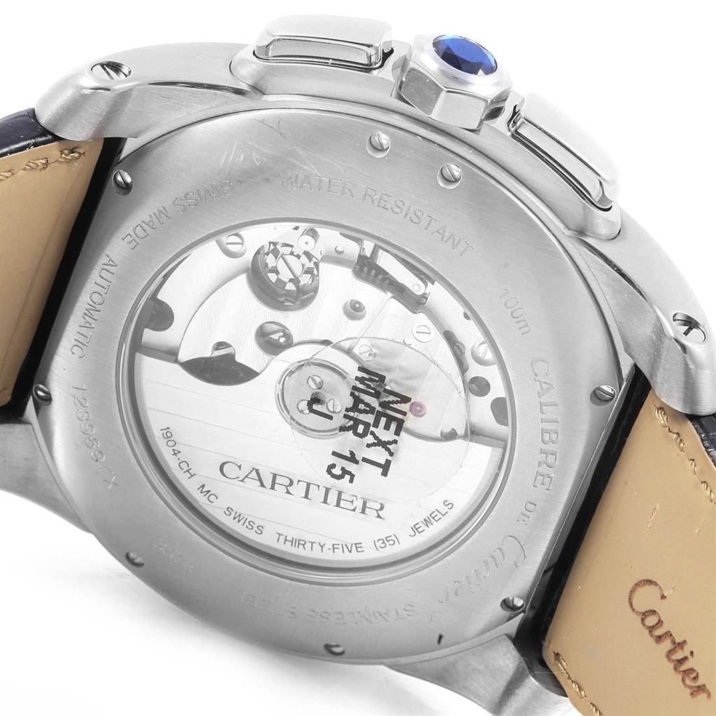 The image shows the back view of a Calibre de Cartier watch by Cartier, highlighting the movement and sapphire crown.