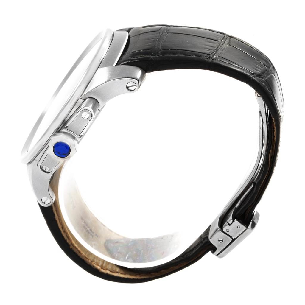 This side-angle view of the Calibre de Cartier watch by Cartier shows the watch face, crown with a blue jewel, and black leather strap.