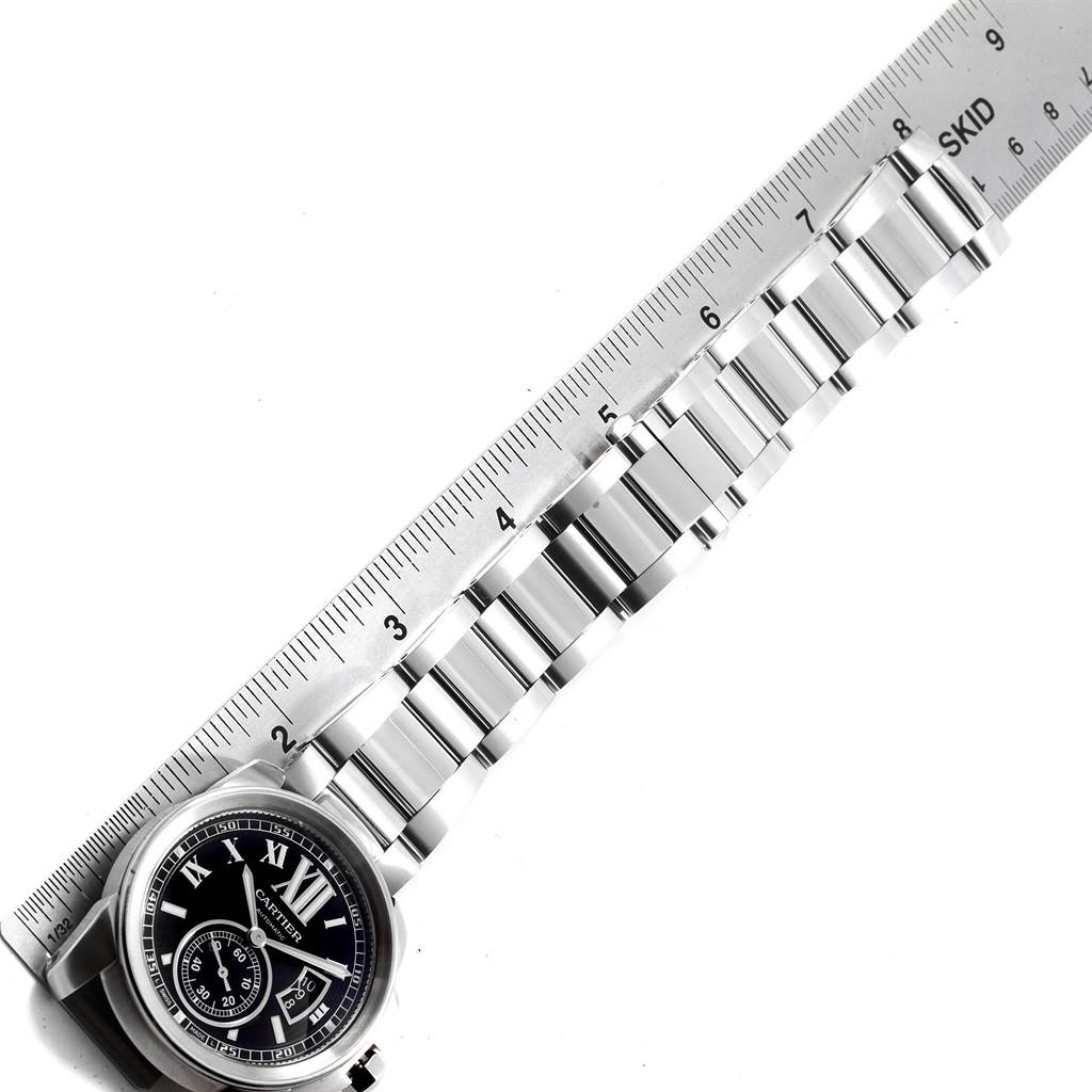 The image shows the face and metal bracelet of the Calibre de Cartier watch by Cartier, along with a ruler for scale.