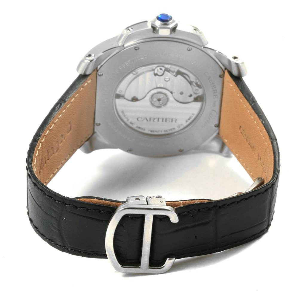 The image shows the back view of the Calibre de Cartier watch by Cartier, highlighting the movement and the leather strap with its buckle.