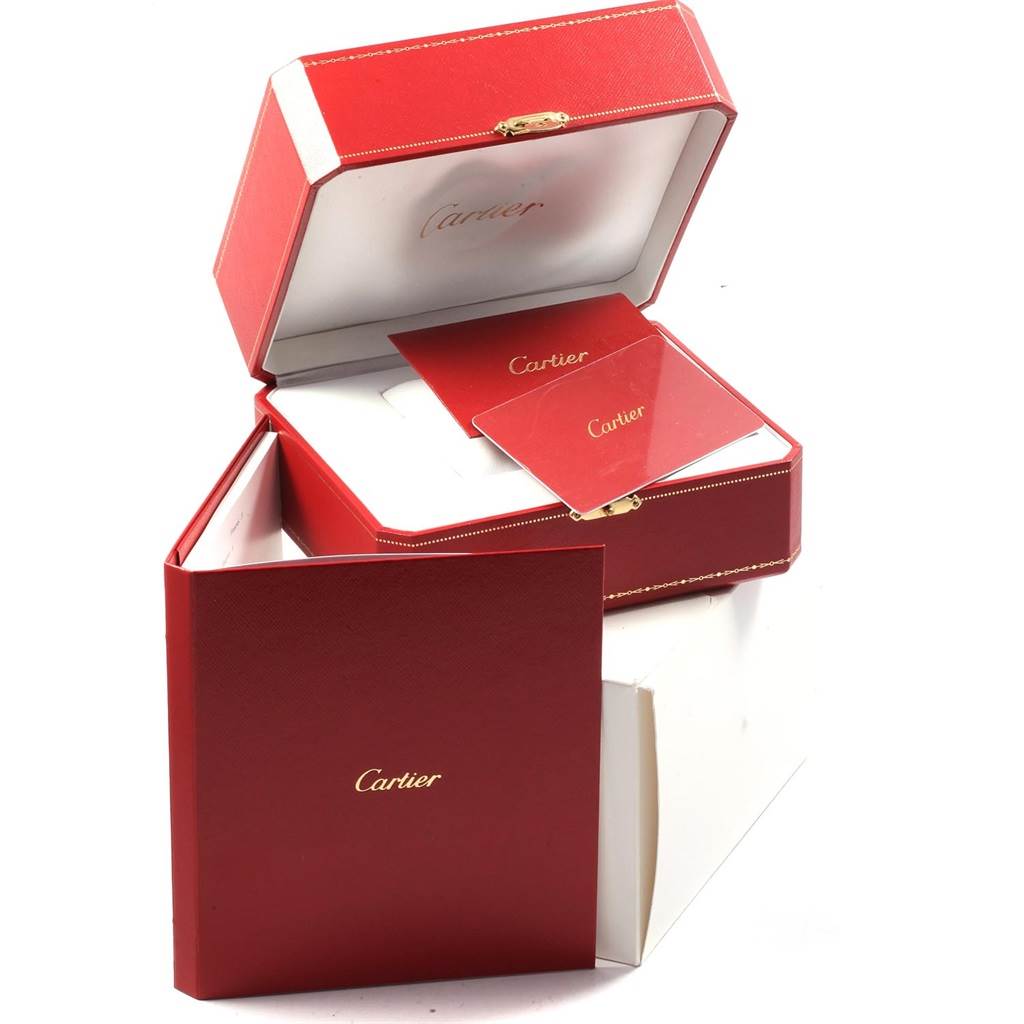 The image shows the packaging and accessories, including a red box and booklets, for a Calibre de Cartier model by Cartier.
