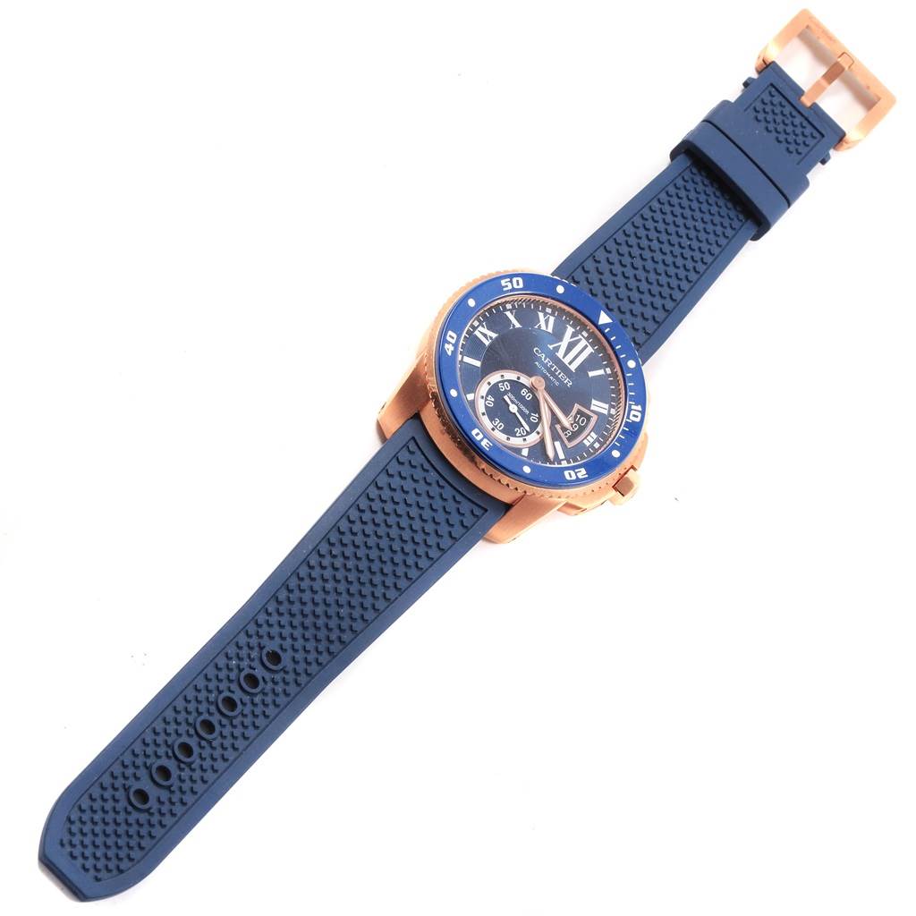 This image shows a top view of a Calibre de Cartier watch by Cartier, featuring a blue rubber strap and gold-tone case.