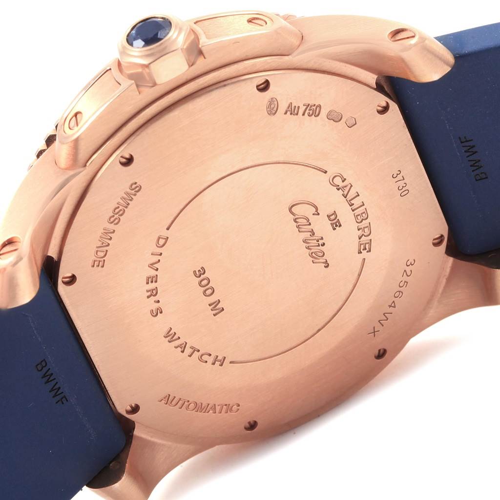 The image shows the back case and crown of a Calibre de Cartier watch by Cartier, with engraved details and a blue strap.