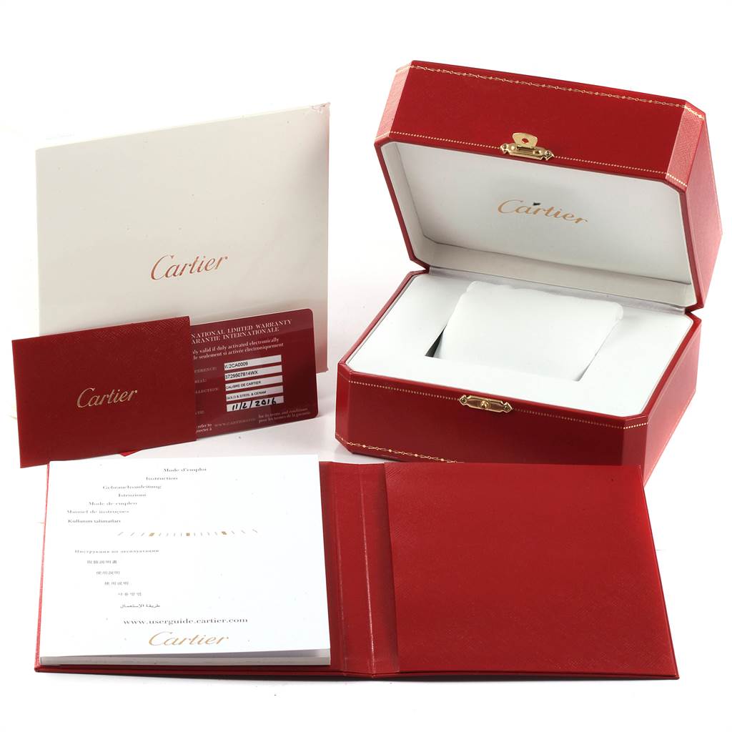 The image shows an open Cartier box, warranty card, manuals, and paperwork for the Calibre de Cartier model.