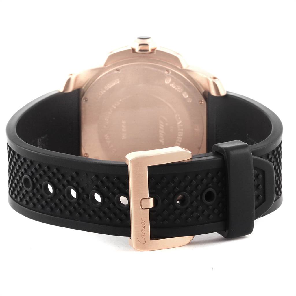 The image shows the back of a Calibre de Cartier watch by Cartier, focusing on the case back and black rubber strap with a buckle.