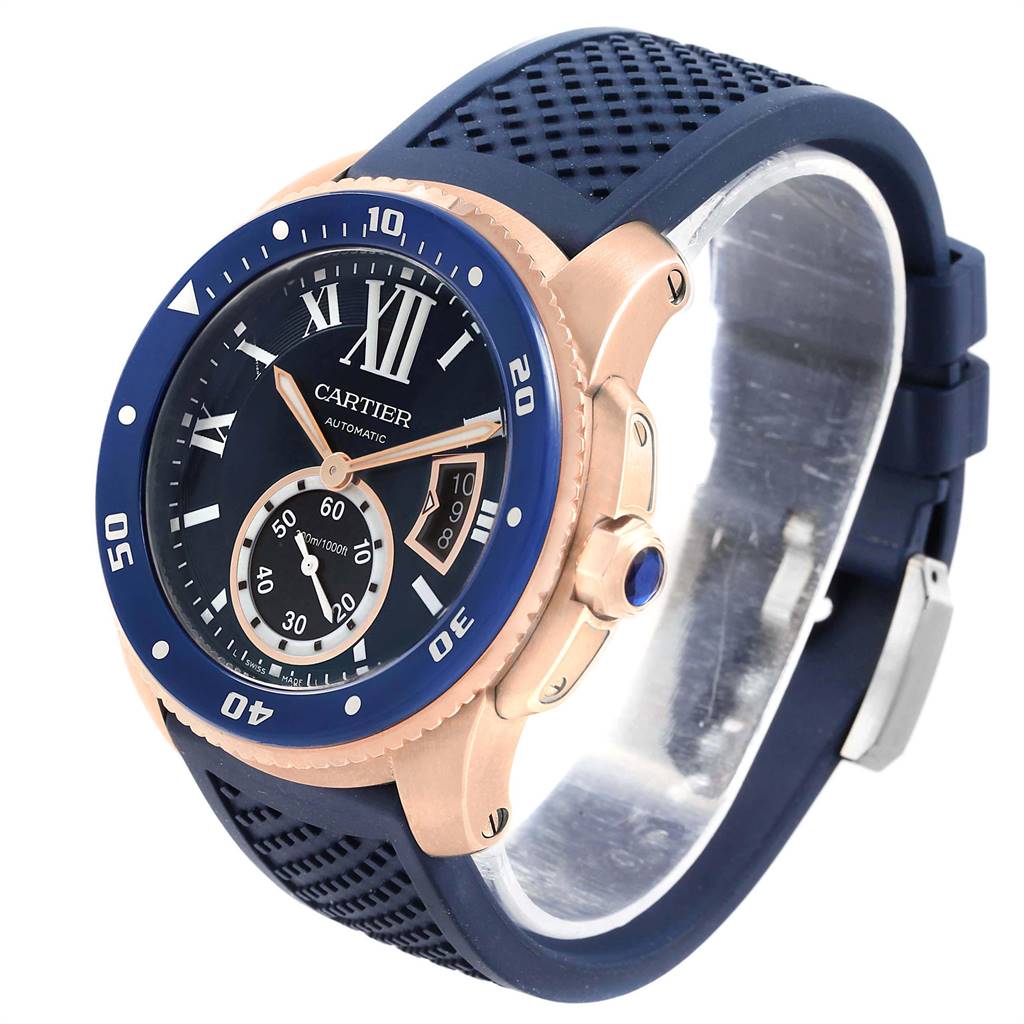 The image shows a Calibre de Cartier watch by Cartier at a three-quarters angle, highlighting its blue dial, bezel, and rubber strap.