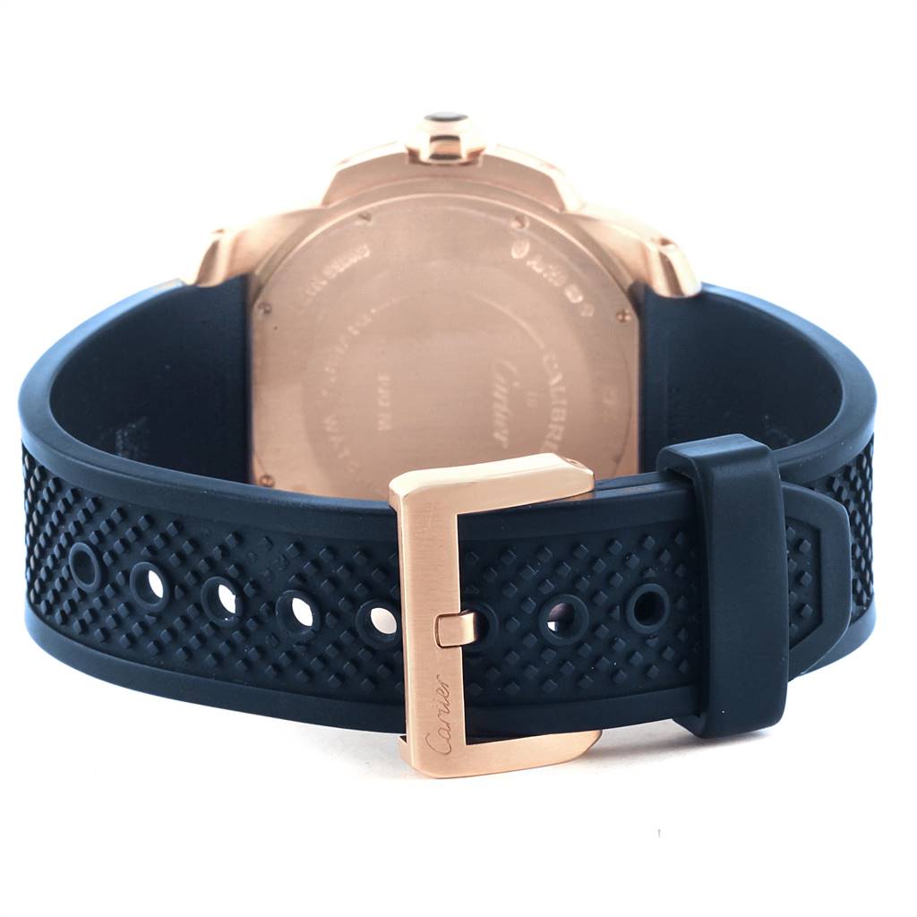 The image shows the back view and clasp of a Calibre de Cartier watch by Cartier, featuring a rubber strap and gold buckle.