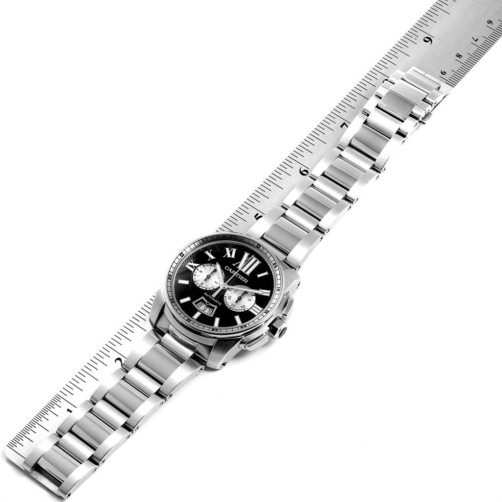 The image shows the front view of a Calibre de Cartier watch by Cartier, along with its metal bracelet and a measuring ruler.