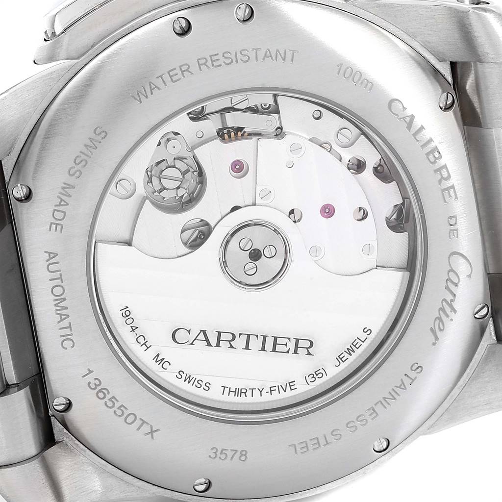 The image shows the backside of the Calibre de Cartier watch by Cartier, revealing the internal movement through a transparent case back.