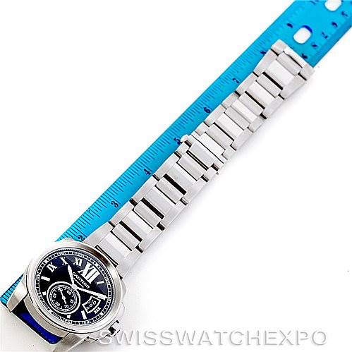 The image shows the Calibre de Cartier watch by Cartier, displaying the full watch and metal bracelet alongside a ruler.