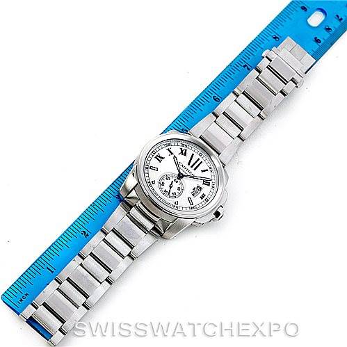 The image shows a top-down view of a Calibre de Cartier watch by Cartier, lying next to a blue ruler.