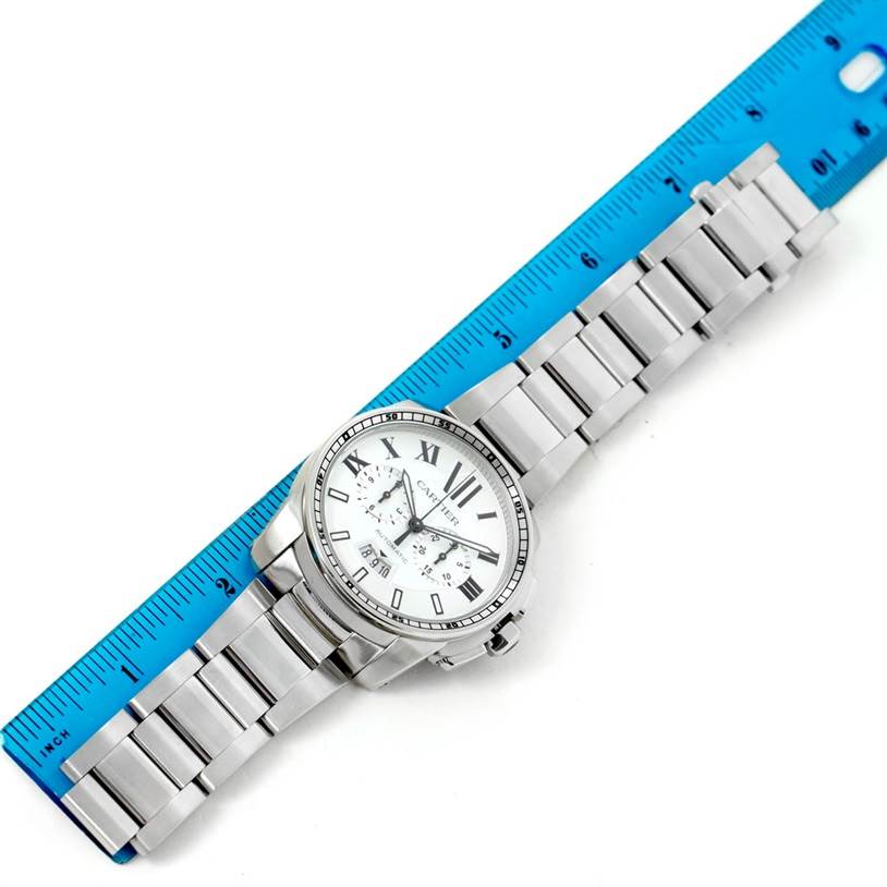 The image shows a Calibre de Cartier watch by Cartier from a top-down angle beside a ruler for scale.