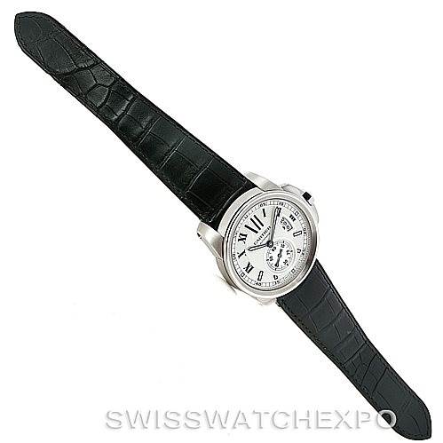 The Calibre de Cartier watch by Cartier is shown from a top-down angle, displaying its face, bezel, and black leather strap.