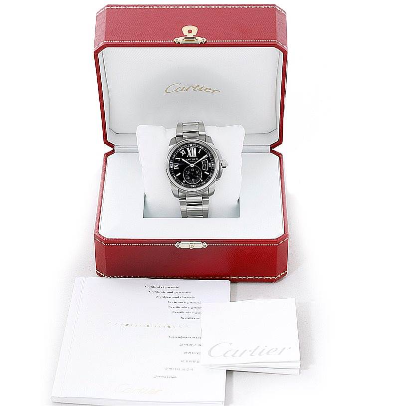 The Calibre de Cartier watch by Cartier is displayed frontally in an opened red Cartier box, with documentation placed beside it.