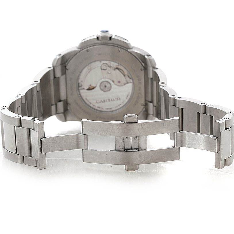 The image shows the back of the Calibre de Cartier watch by Cartier, highlighting the open clasp and the movement inside the case.