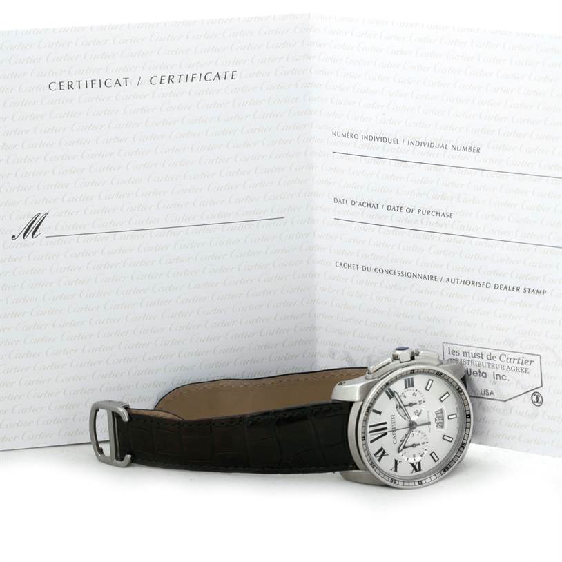 The image shows a side view of the Calibre de Cartier watch by Cartier, with its certificate booklet in the background.