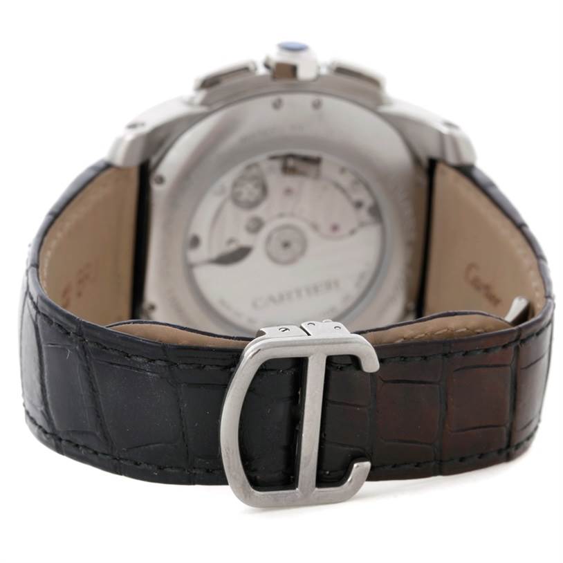The image shows the back view of the Calibre de Cartier watch by Cartier, displaying its movement and leather strap with a buckle.