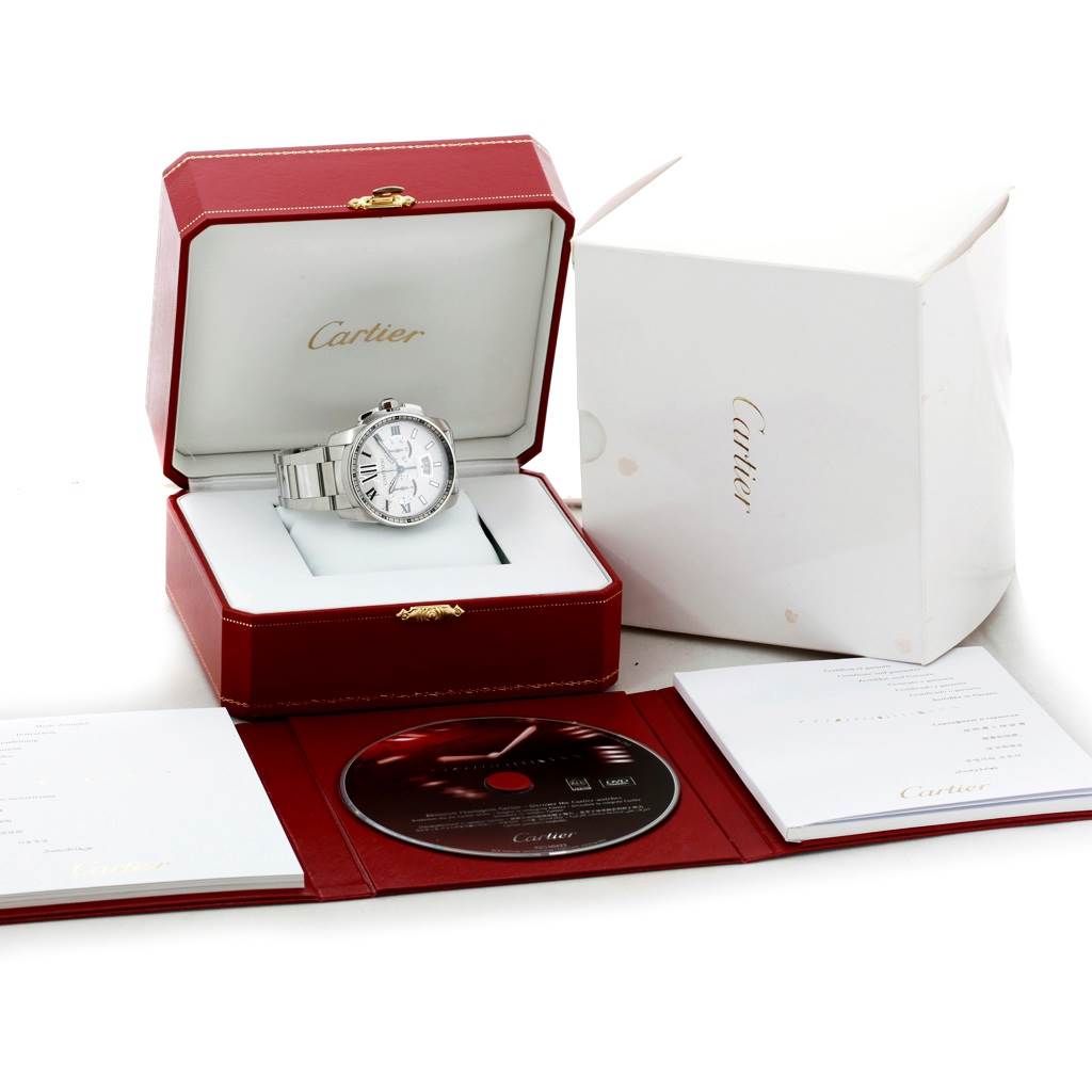 The Calibre de Cartier watch by Cartier is shown in its open box, accompanied by a booklet and CD.