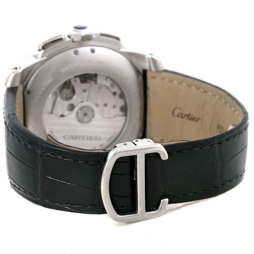The image shows the back view of a Calibre de Cartier watch by Cartier, highlighting the movement mechanism, leather strap, and buckle.
