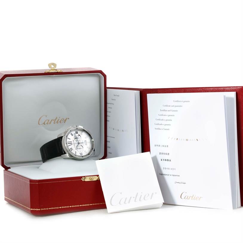The Calibre de Cartier watch and accessories are displayed in an open red Cartier box with booklets.