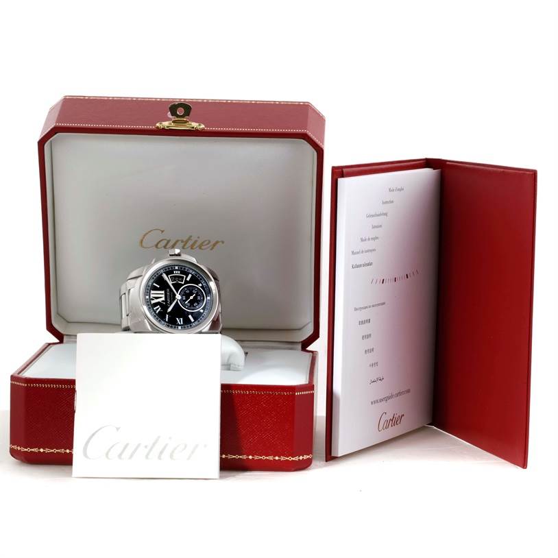 The Calibre de Cartier watch is displayed in its open box along with a booklet and a white card, all branded with Cartier.