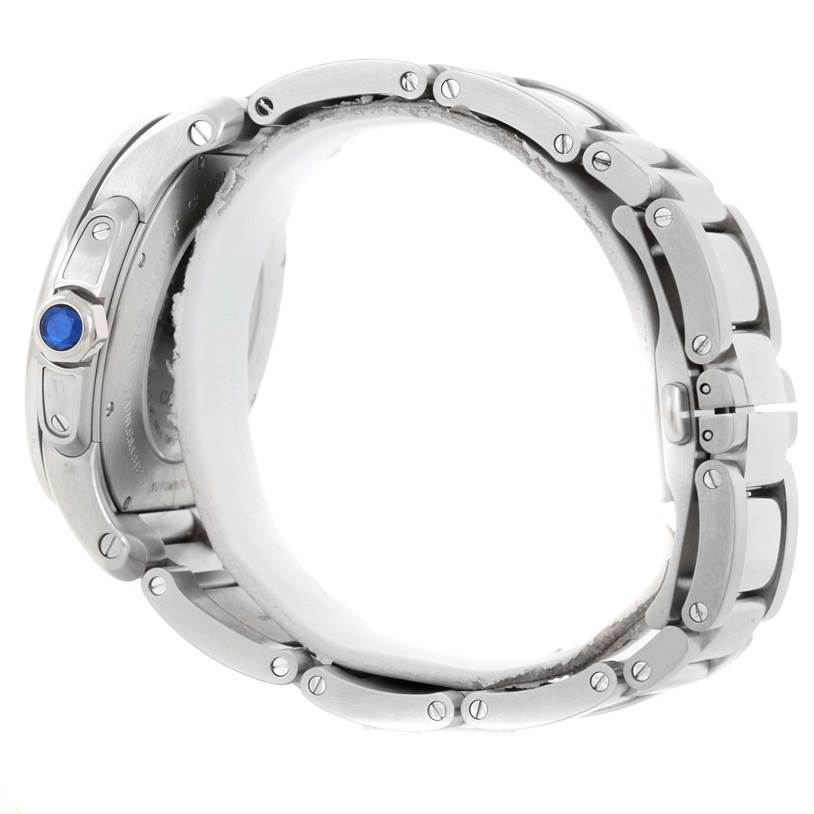 The image shows the side view of a Calibre de Cartier watch by Cartier, highlighting the bracelet and crown with a blue cabochon.