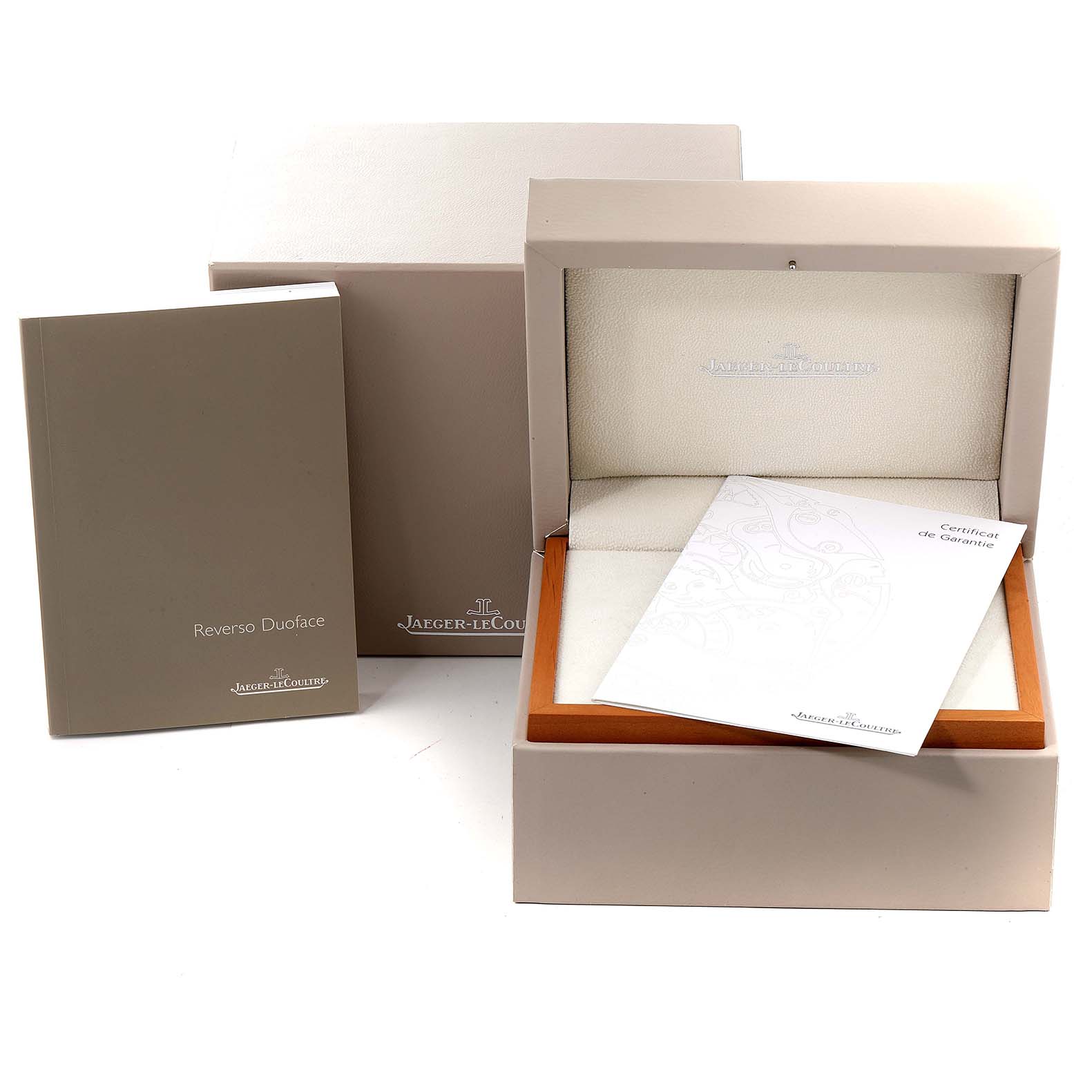 The image shows packaging and documentation for a Jaeger-LeCoultre Reverso model, including the watch box, manual, and warranty card.
