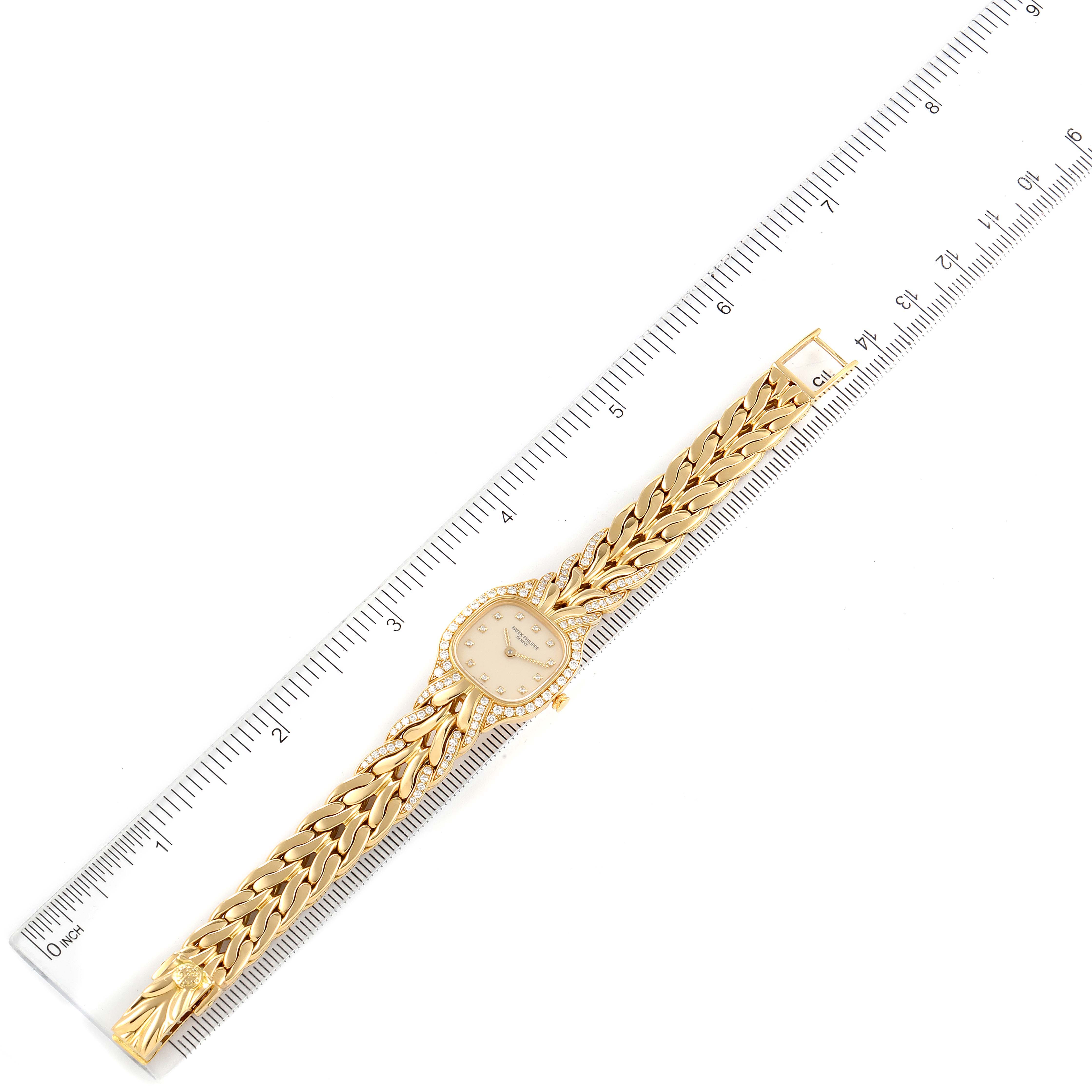 The image shows a top view of the Patek Philippe La Flamme  4715J Women's Yellow Gold Silver Dial 4715J Women's Yellow Gold Silver Dialwatch with a gold strap next to a ruler for scale.