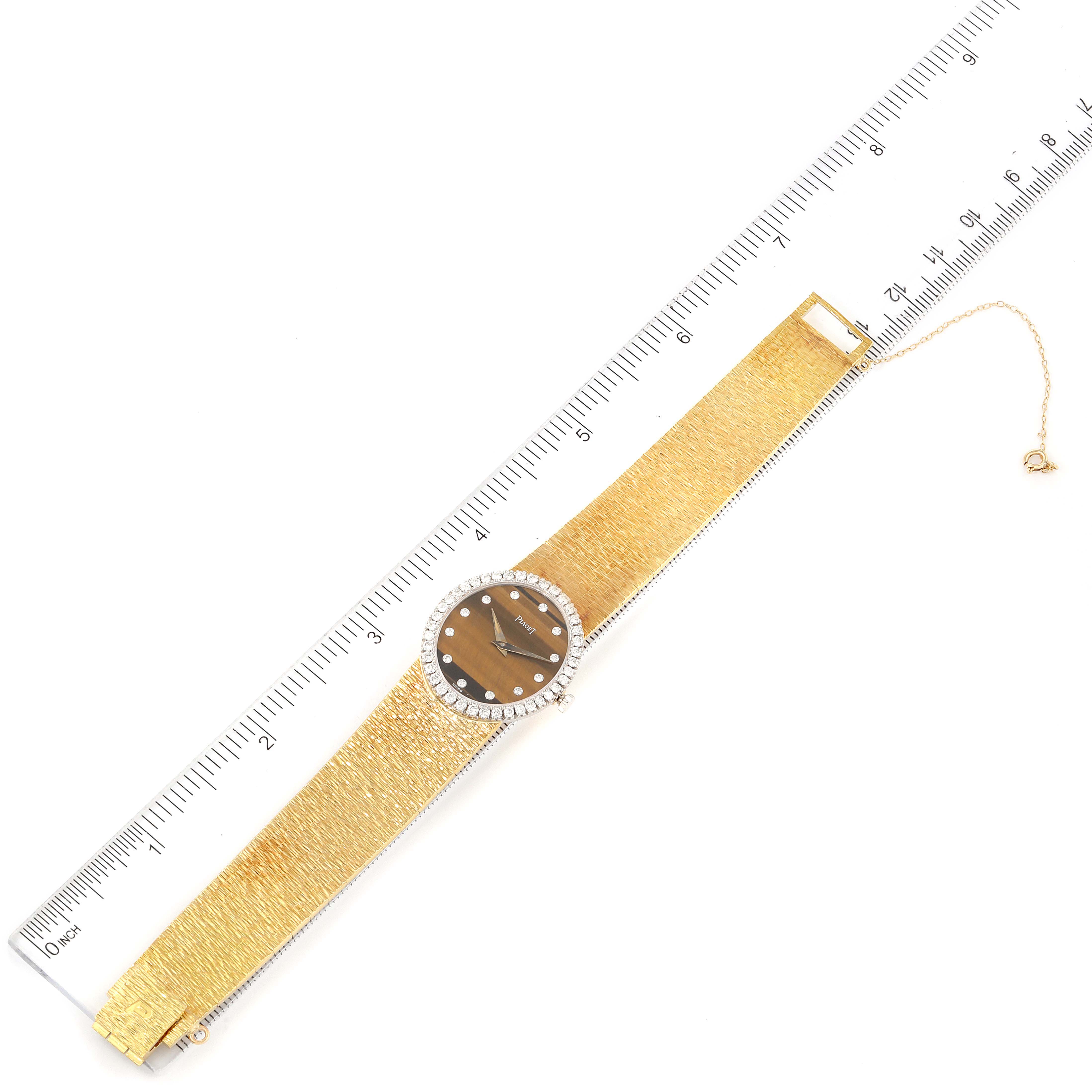 The Piaget 9826-A-6 Women's Yellow Gold Brown Dial 9826-A-6 Women's Yellow Gold Brown Dial 9826 model Yellow Gold Diamond Tiger Eye Stone Dial Vintage Cocktail Ladies Watch is shown lying flat with a ruler for scale.