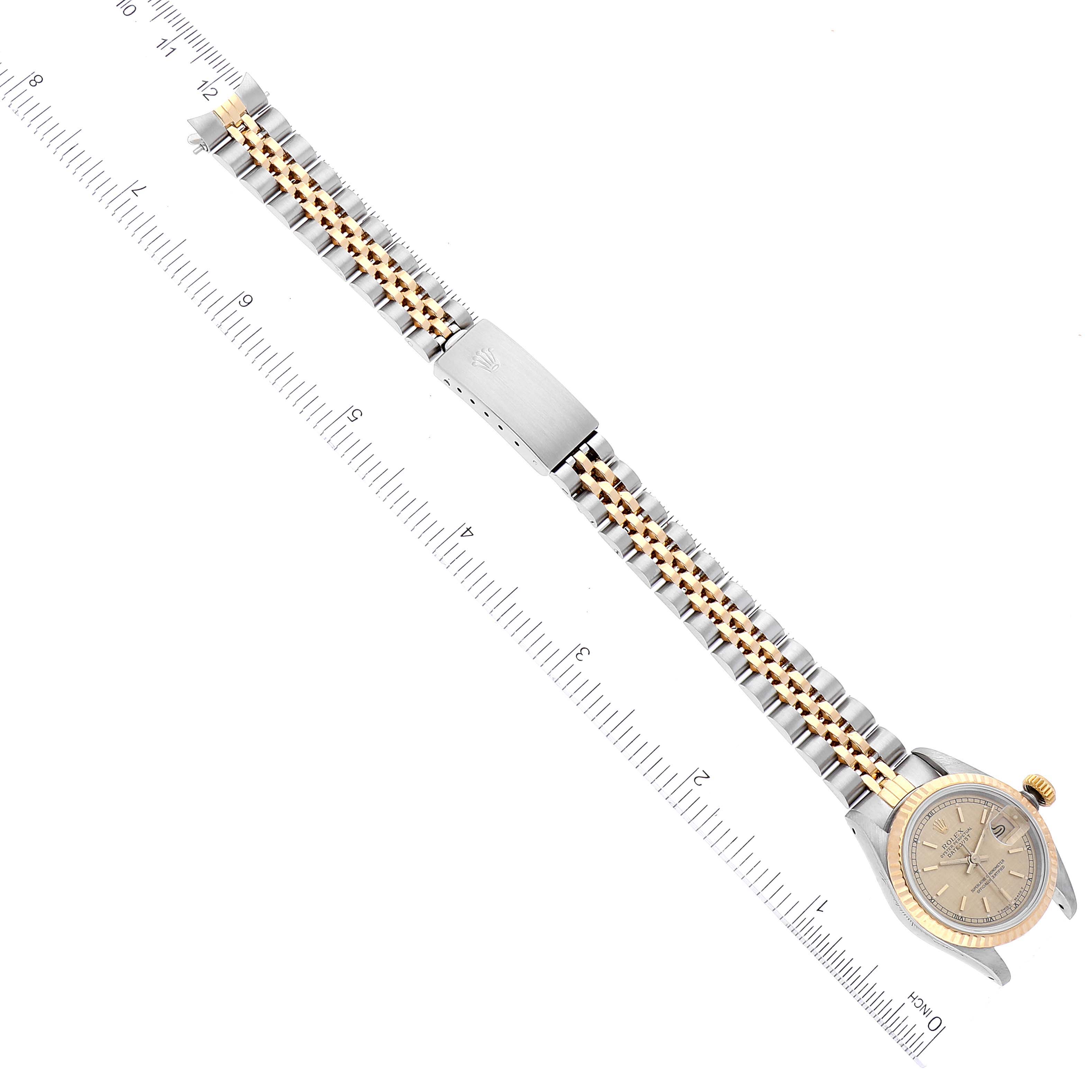 This top-down view of a Rolex Datejust 69173 Women's Steel and Gold (two tone) Champagne Dial 69173 Women's Steel and Gold (two tone) Champagne Dial model showcases the watch face, bezel, and full bracelet against a ruler background.