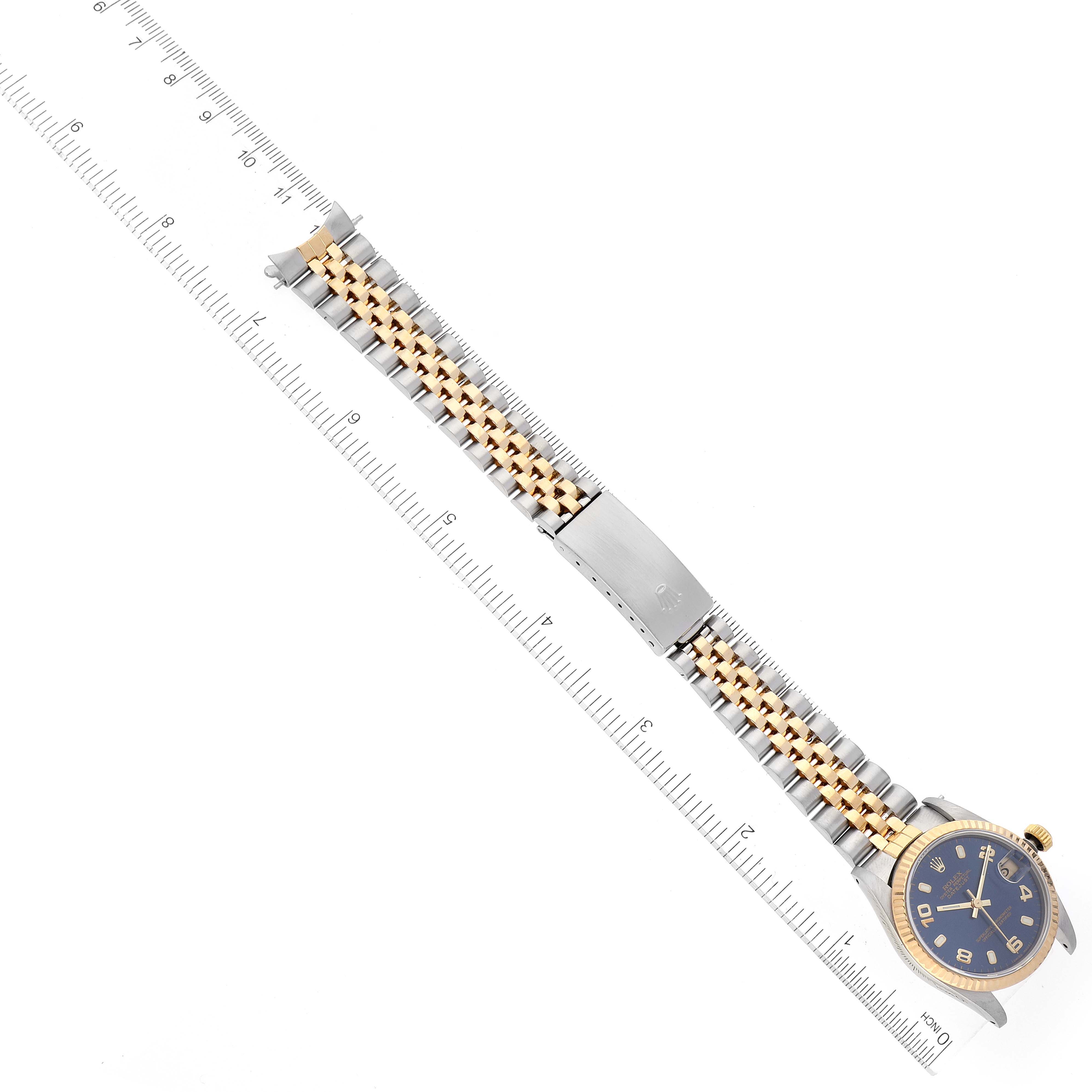The Rolex Mid-Size 68273 Women's Steel and Gold (two tone) Blue Dial 68273 Women's Steel and Gold (two tone) Blue Dial watch is shown from a top-down angle, displaying the face, bezel, bracelet, and clasp alongside a measuring scale.
