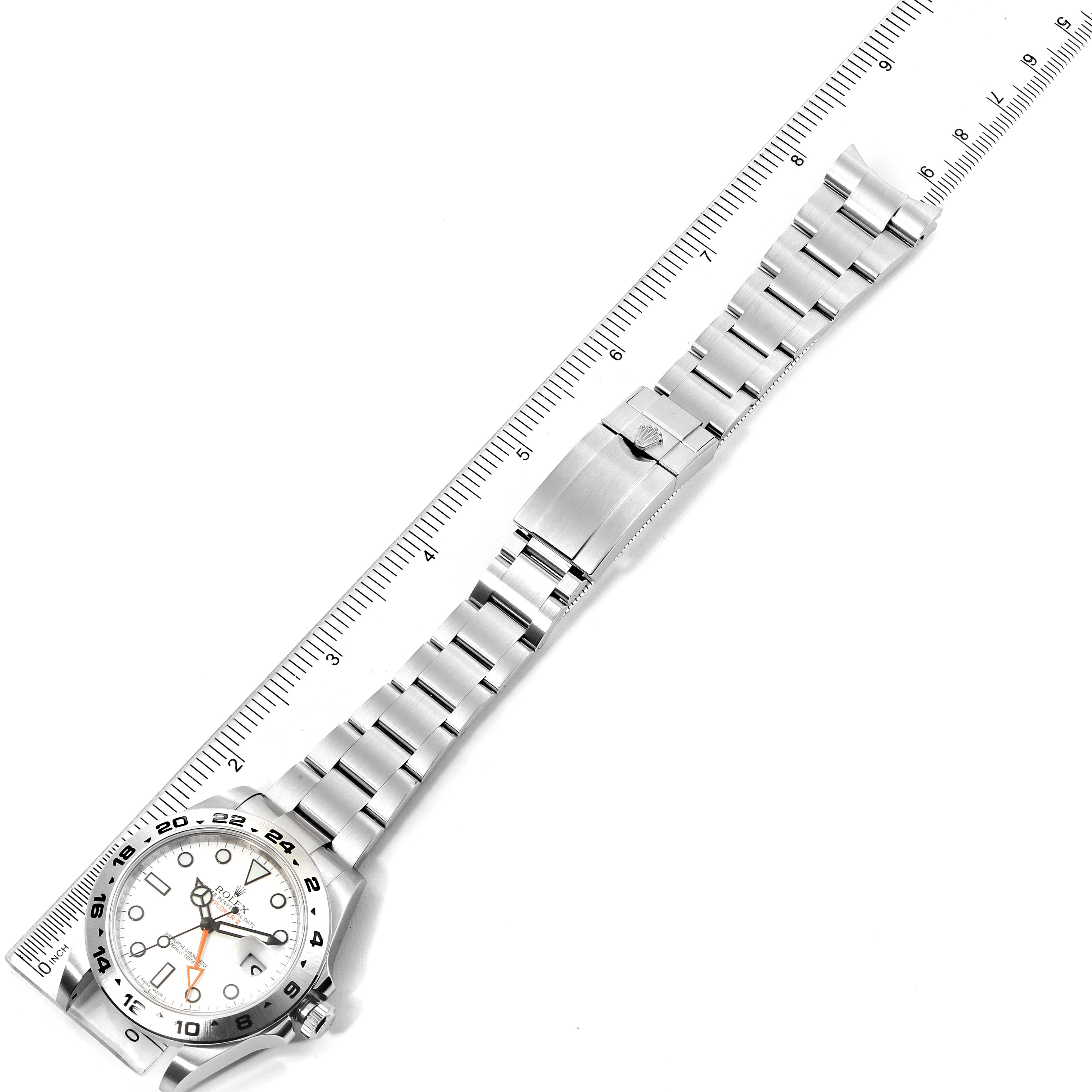 This image shows a top-down view of a Rolex Explorer 216570 Men
s Stainless Steel White Dial 216570 Men
s Stainless Steel White Dial watch, including the face, bezel, bracelet, and clasp beside a ruler.