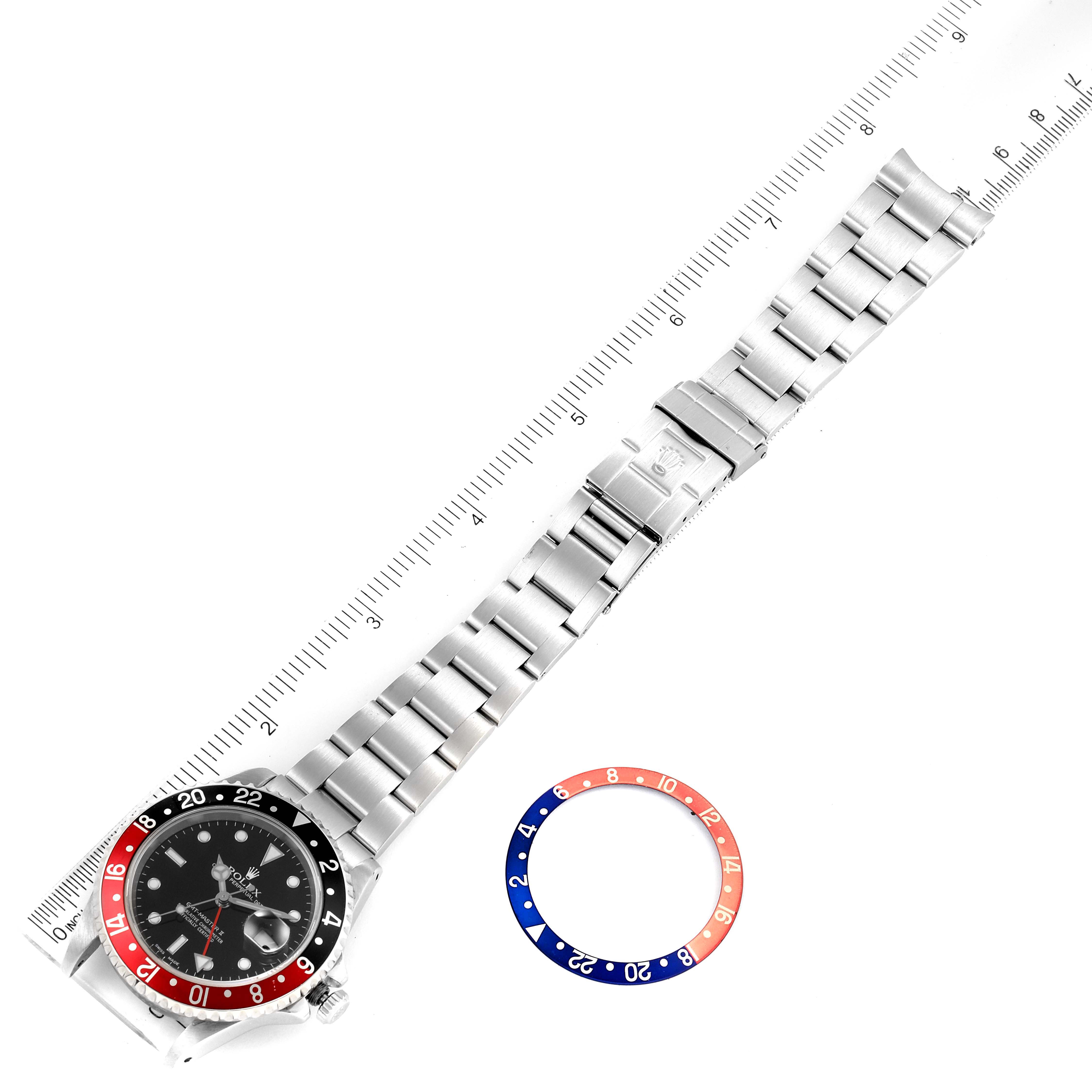 The image shows a Rolex GMT-Master 16710 Men
s Stainless Steel Black Dial 16710 Men
s Stainless Steel Black Dial model watch laid flat alongside a measurement ruler, with an additional bezel insert placed separately.