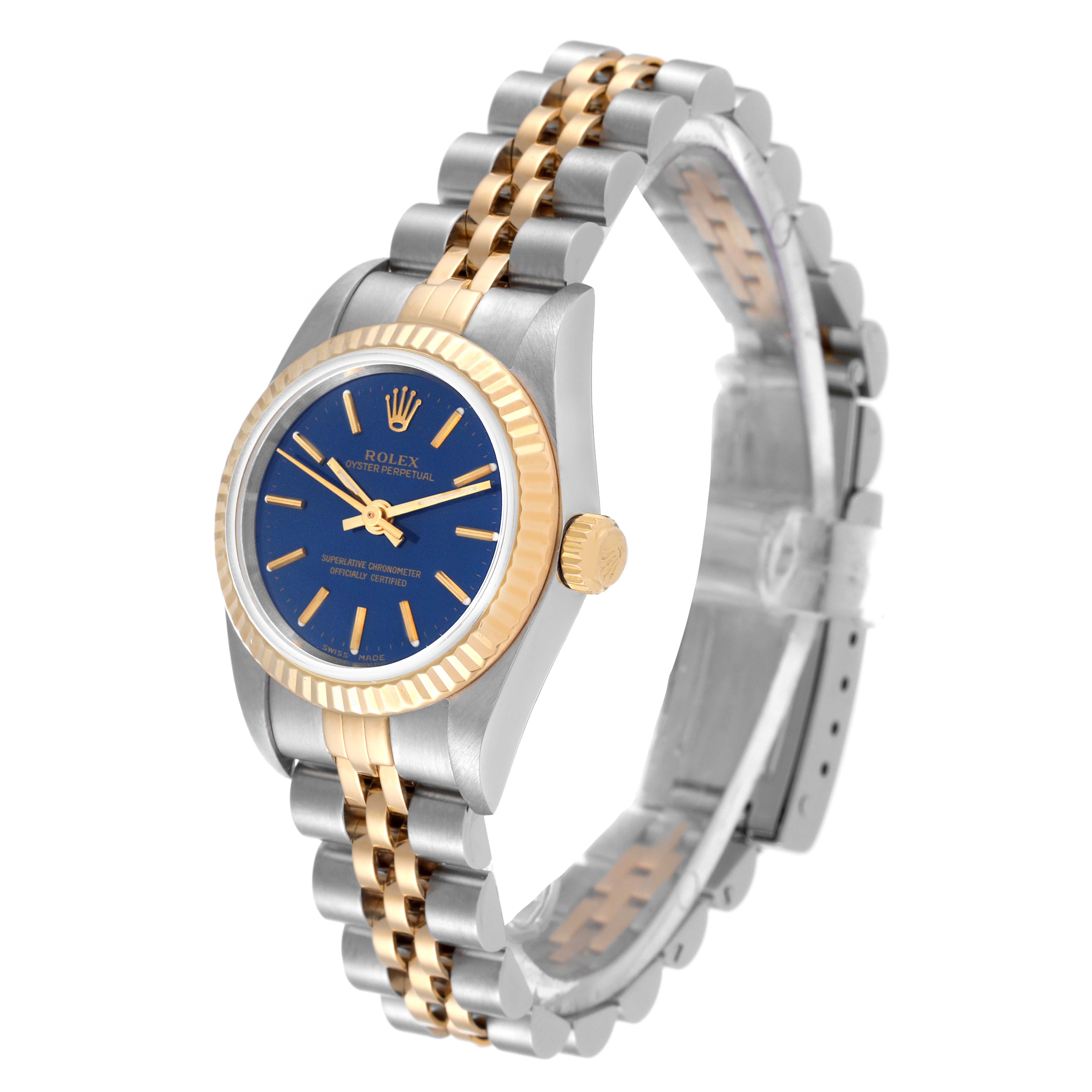 The image shows a side-angle view of a Rolex Oyster Perpetual 76193 Women
s Steel and Gold (two tone) Blue Dial 76193 Women
s Steel and Gold (two tone) Blue Dial watch, highlighting its blue dial, gold bezel, crown, and two-tone bracelet.