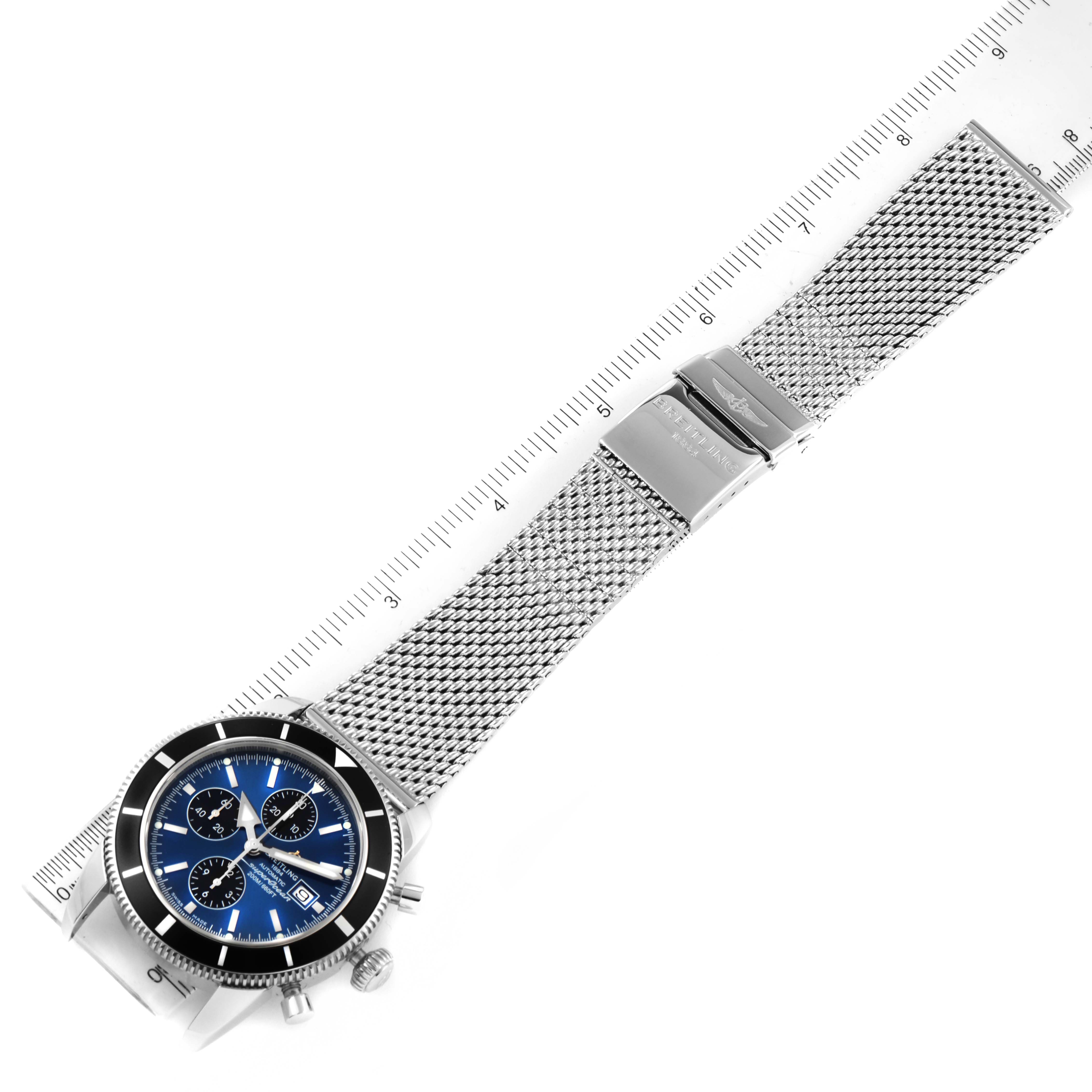 The image shows a Breitling Superocean A13320 Men's Stainless Steel Blue Dial A13320 Men's Stainless Steel Blue Dial watch at a slight angle, highlighting its blue dial, mesh bracelet, and clasp, with a ruler for scale.