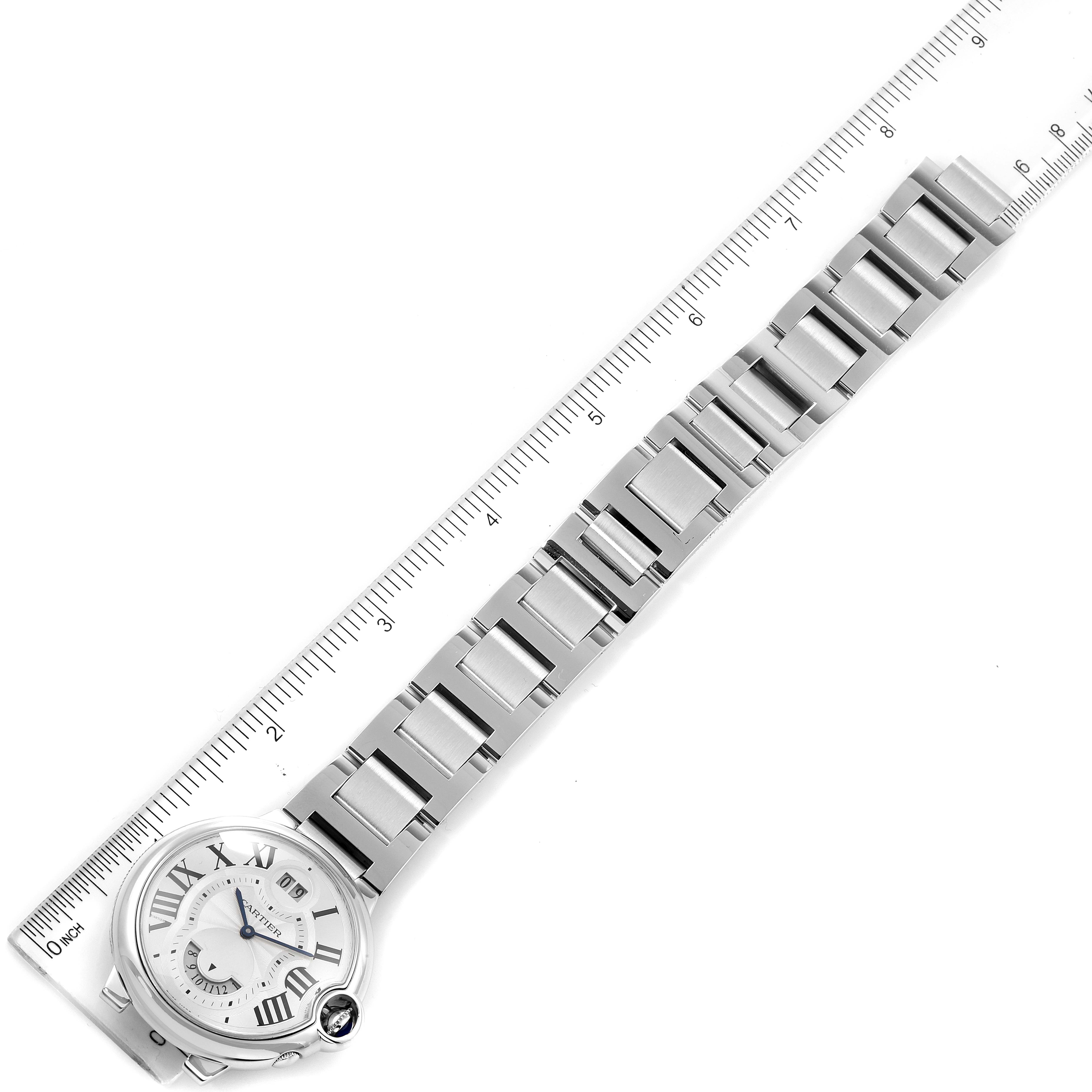 The image shows a Ballon Bleu by Cartier watch laid flat with its band extended alongside a ruler, displaying the face and bracelet.