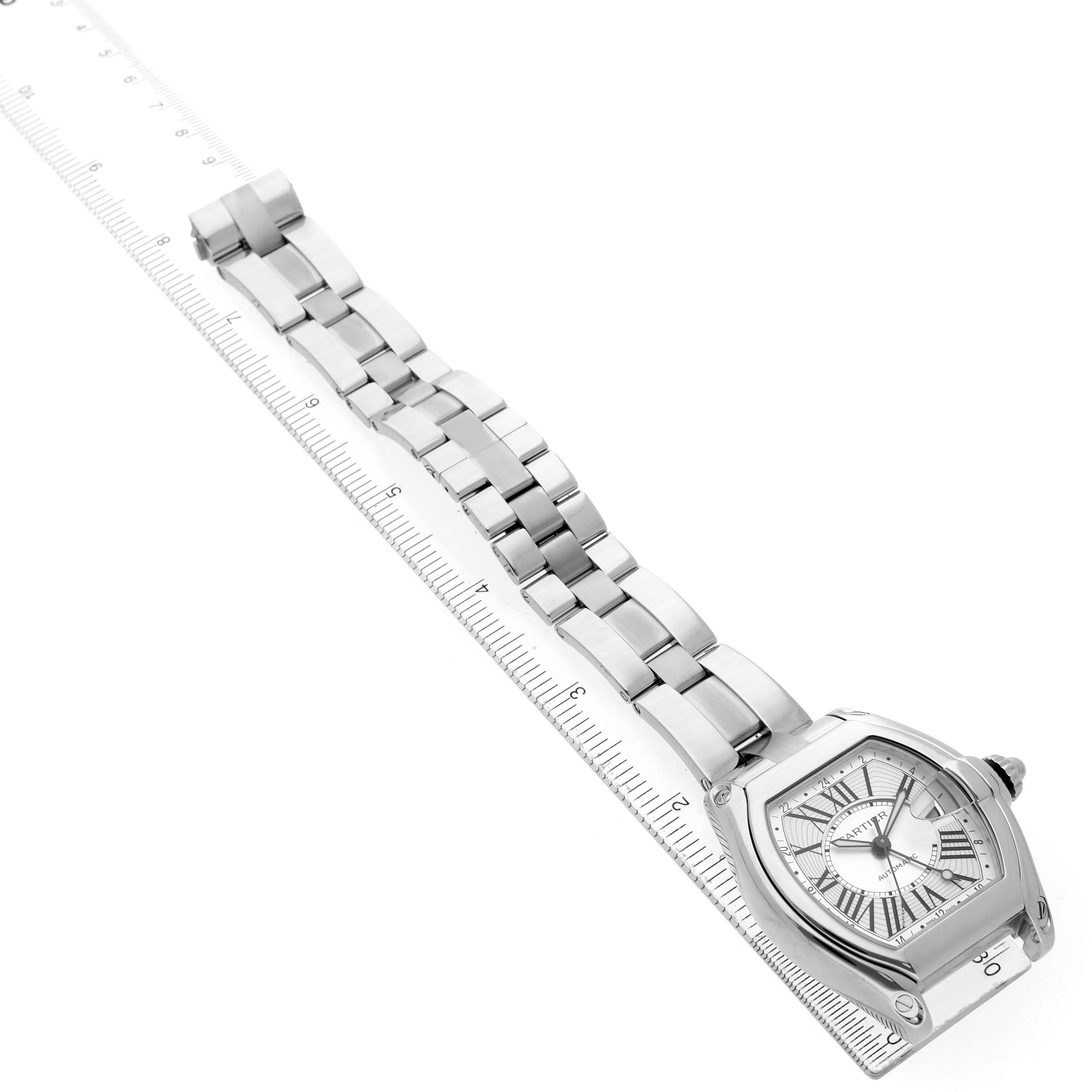 The Cartier Roadster W62032X6 Women's Stainless Steel Silver Dial watch is shown at a diagonal angle, highlighting the face and bracelet alongside a ruler.