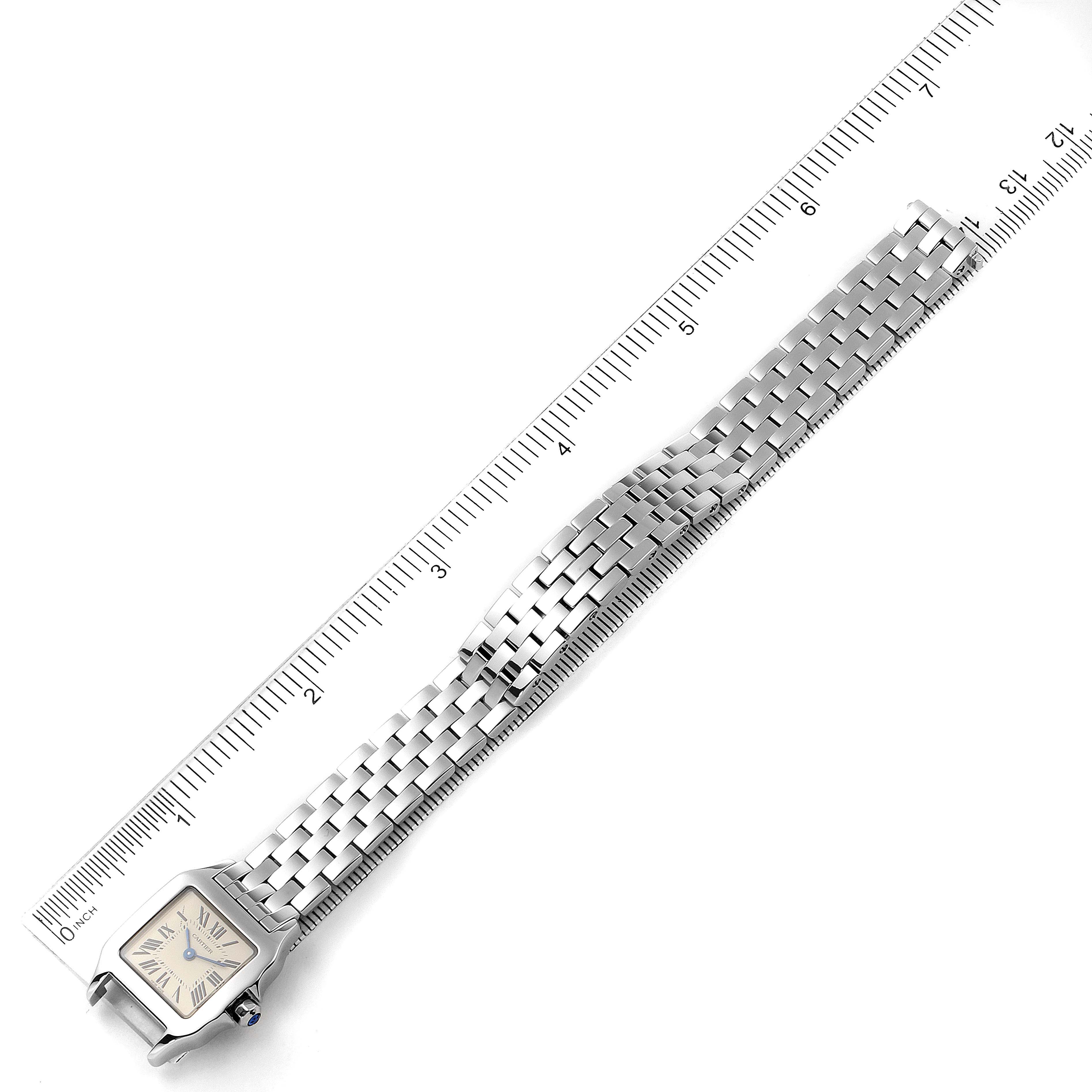 The image shows a top view of a Santos Demoiselle model by Cartier, showcasing the watch face and metal bracelet strap aligned with a ruler.
