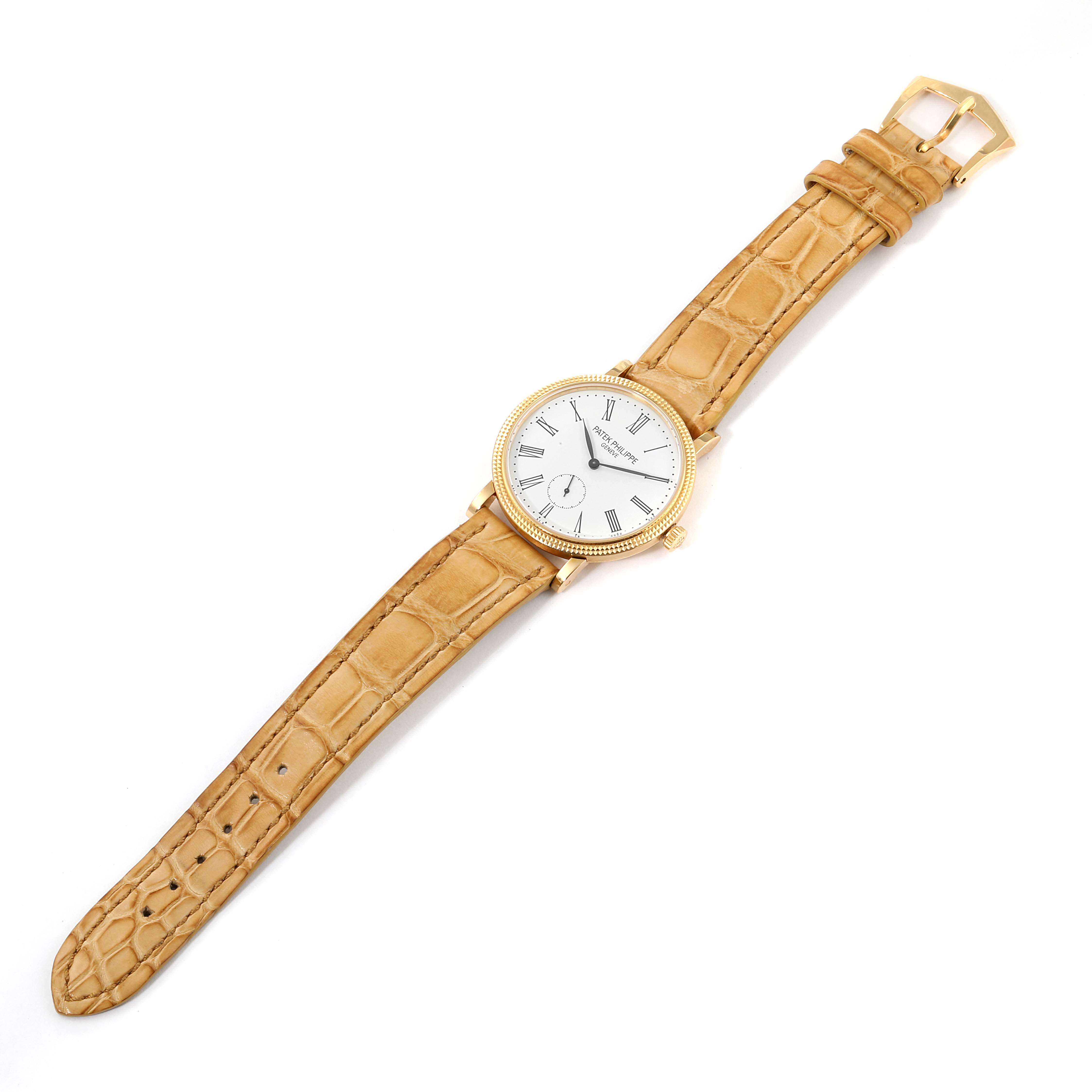 The Patek Philippe Calatrava 7119J Women's Yellow Gold White Dial 7119J Women's Yellow Gold White Dial watch is shown in a top-down angle, displaying its face, bezel, case, and leather strap with the buckle visible.