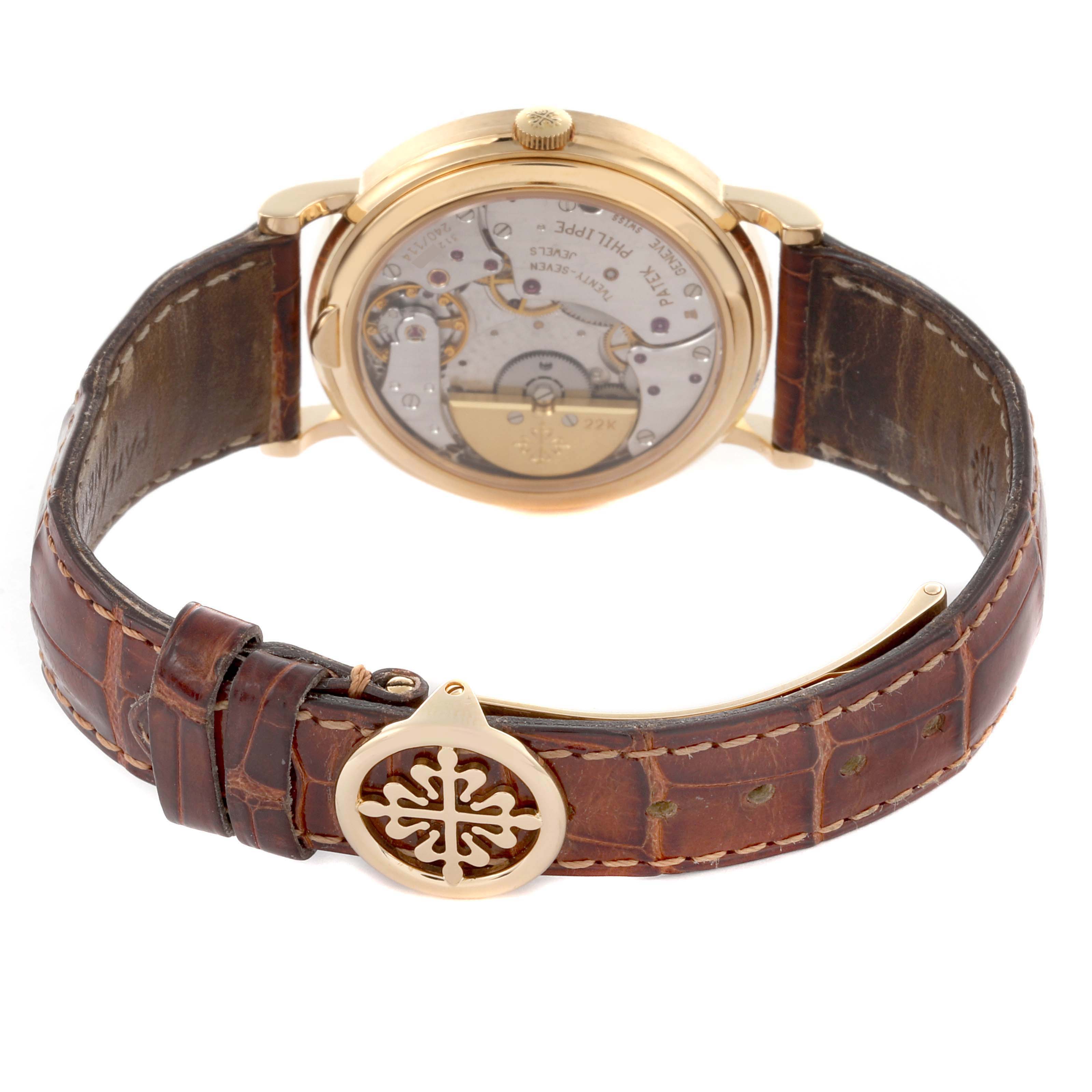 The image shows the back view of a Patek Philippe Complications 5039J-001 Men's Yellow Gold Silver Dial 5039J-001 Men's Yellow Gold Silver Dial watch, highlighting the open movement and partially visible leather strap.