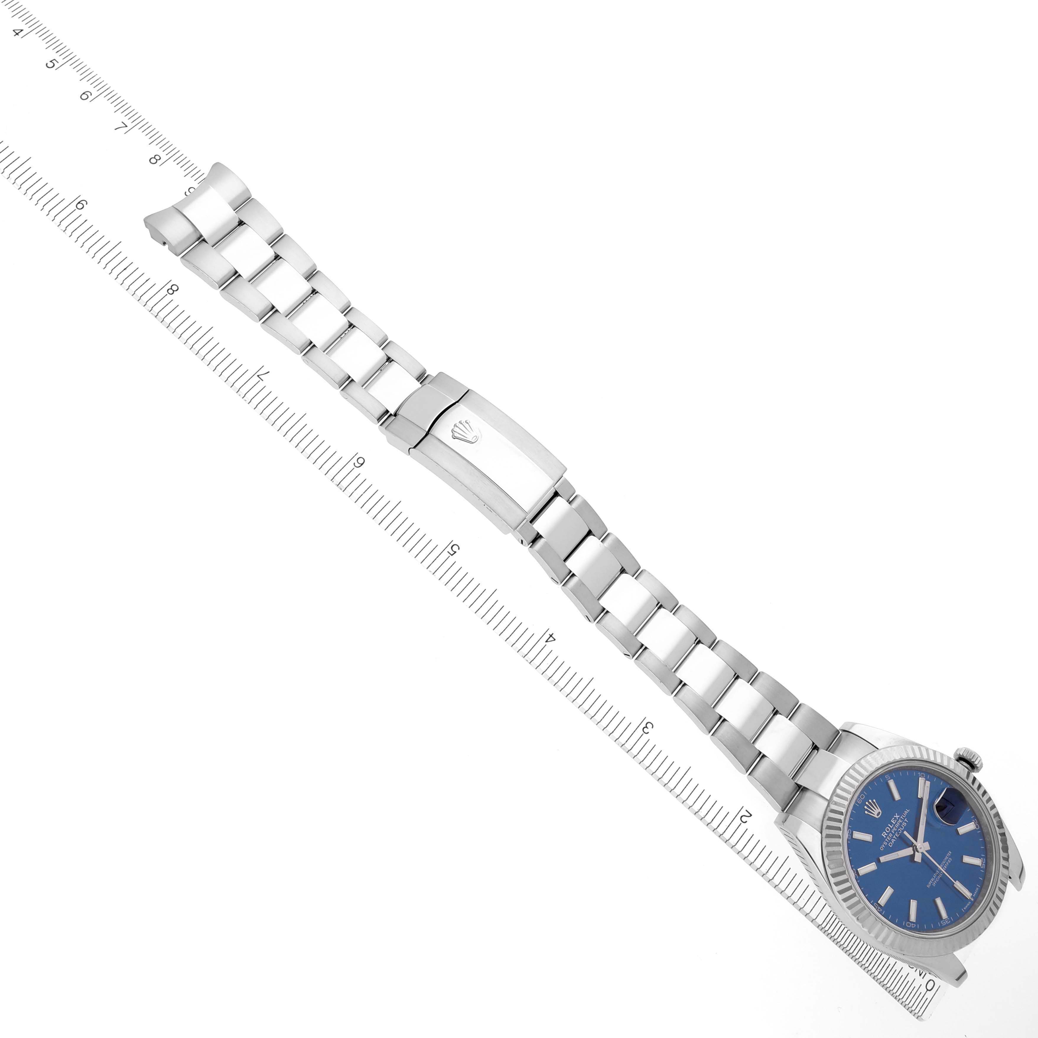 The image shows a top-down view of a Rolex Datejust 41 126334 Men
s Stainless Steel Blue Dial 126334 Men
s Stainless Steel Blue Dial watch with a blue dial and silver bracelet, accompanied by a ruler.