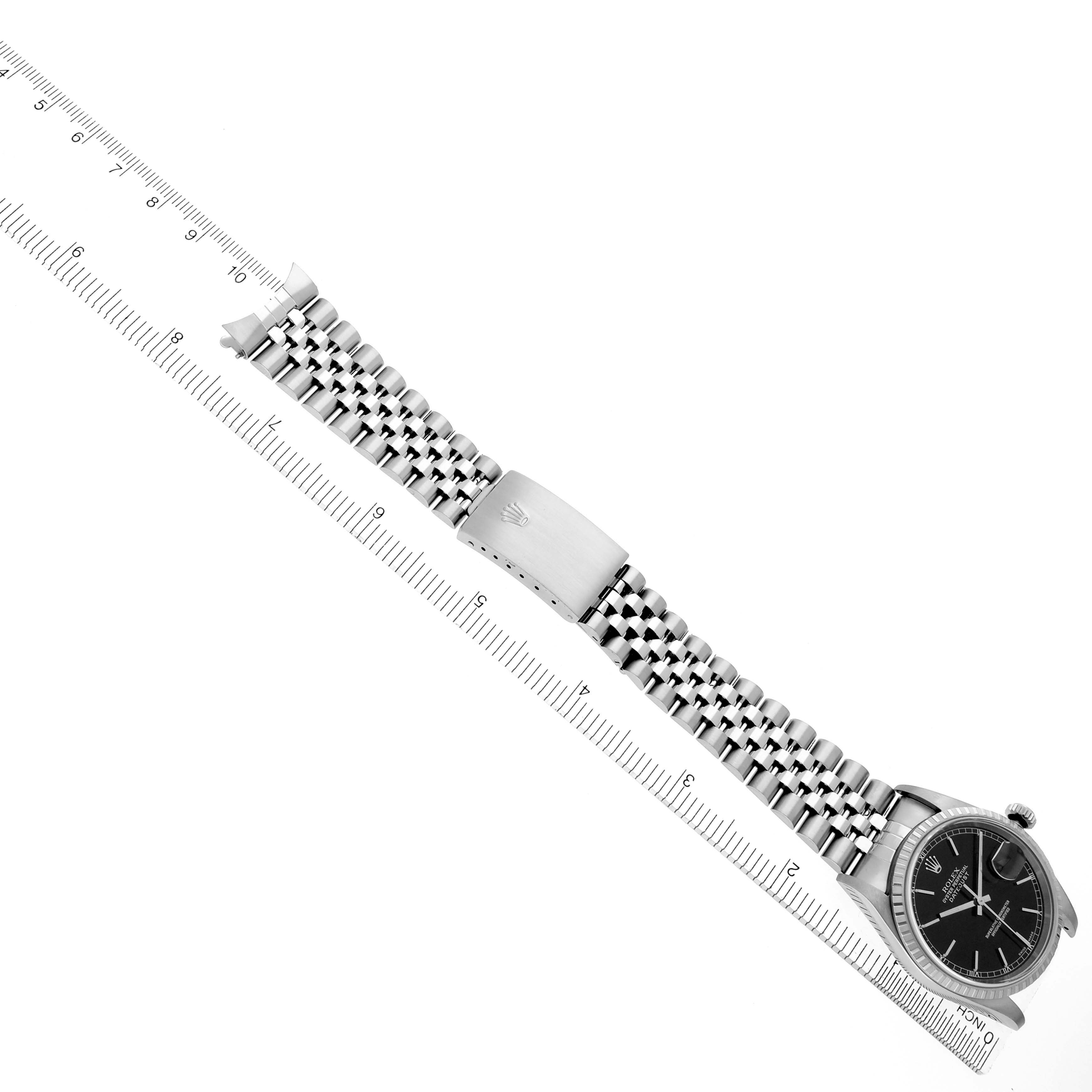 The image shows a Rolex Datejust 16220 Men's Stainless Steel Black Dial 16220 Men's Stainless Steel Black Dial watch at a diagonal angle, displaying the dial, bracelet, and clasp alongside a ruler for scale.